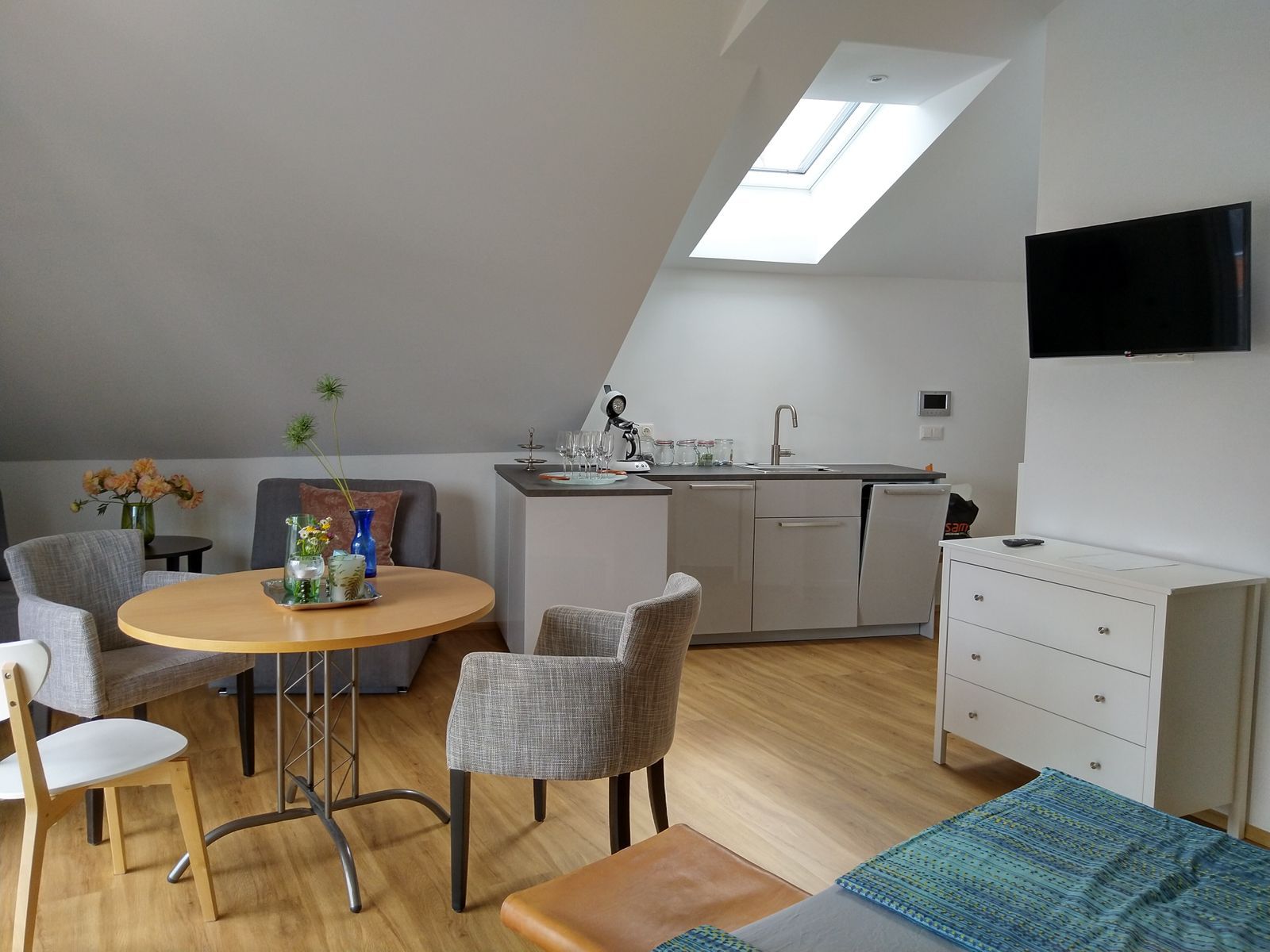 Moderní byt s kuchyňským koutem, jídelním stolem a TV.
