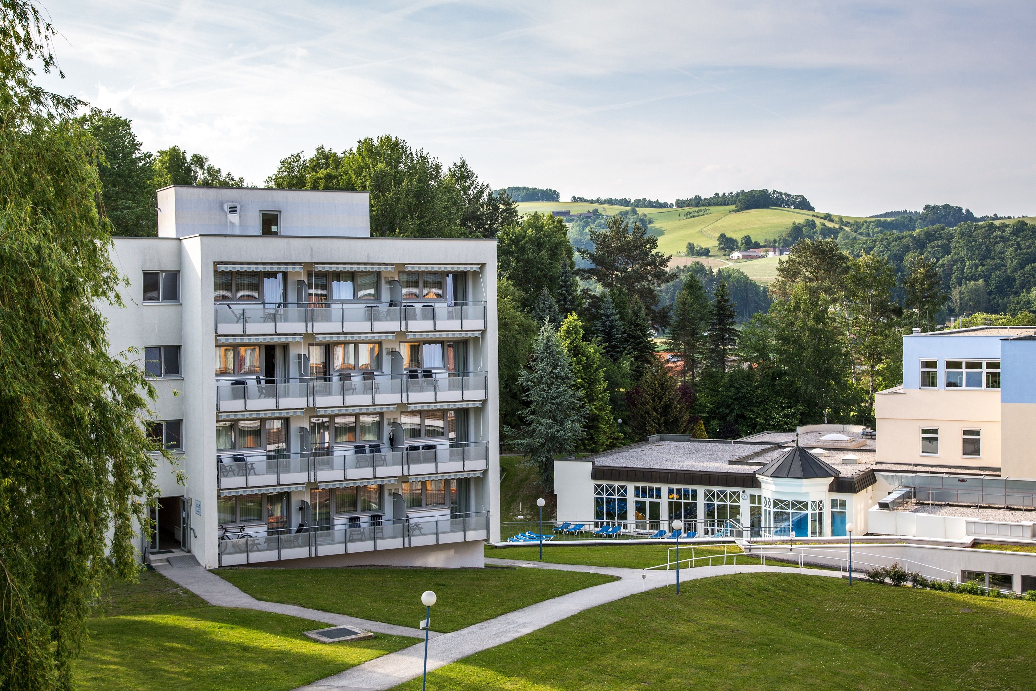 Pohled zvenčí na Parkhotel v lázních Königsberg s okolní zelení.