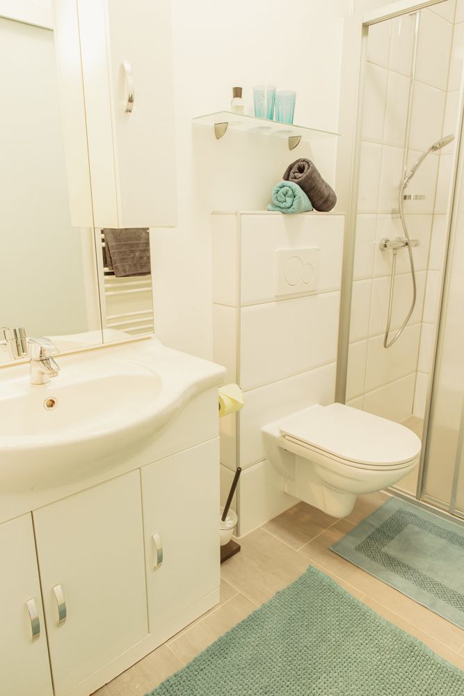 Moderní koupelna se sprchovým koutem, umyvadlem a toaletou.