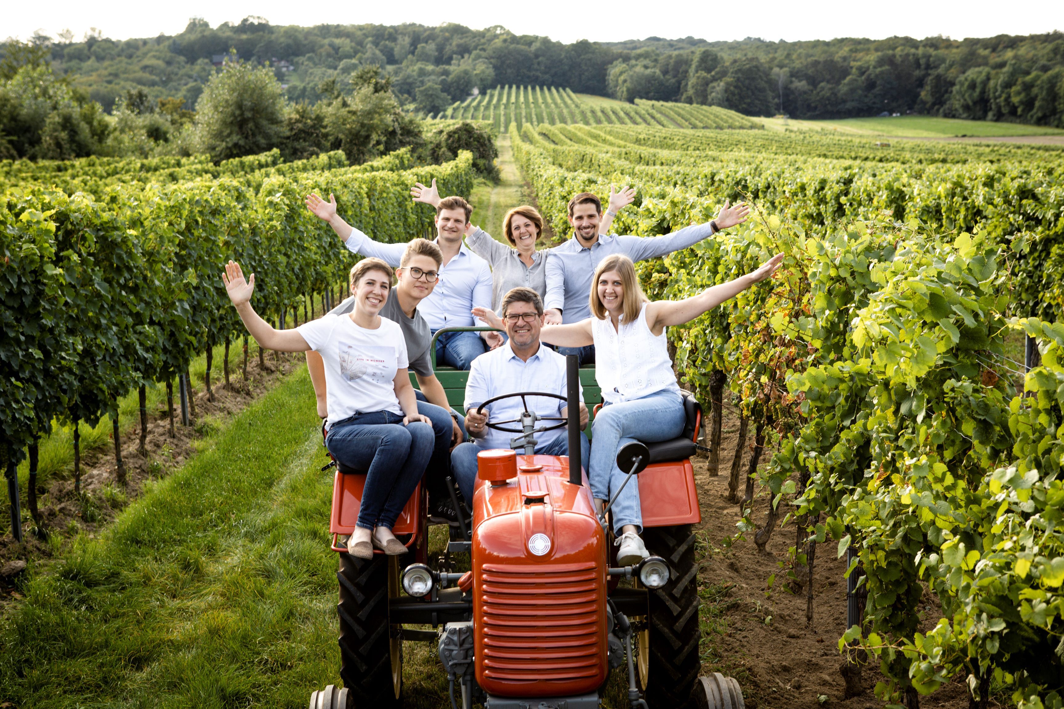 Skupina lidí na traktoru na vinici.