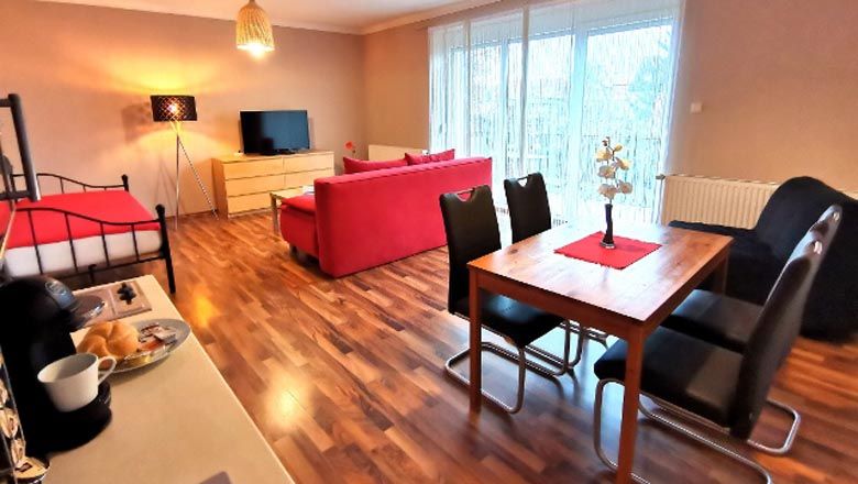 Moderní obývací pokoj s červenou pohovkou, jídelním stolem a TV s plochou obrazovkou.