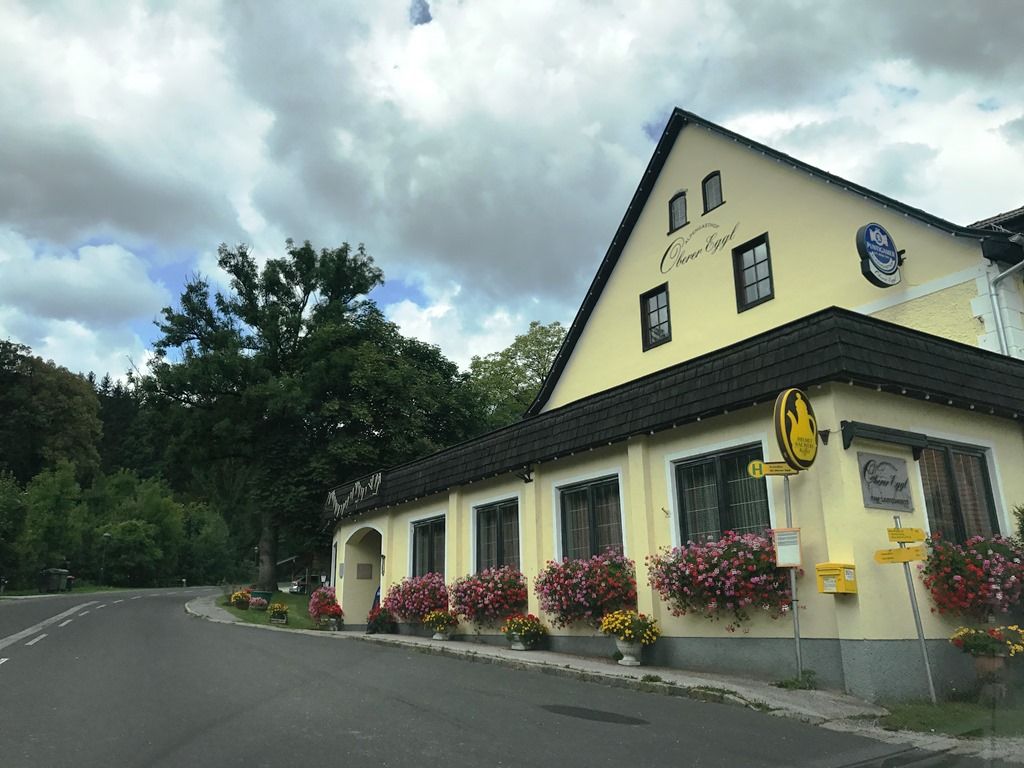 Gasthof Oberer Eggl s květinami a autobusovou zastávkou.