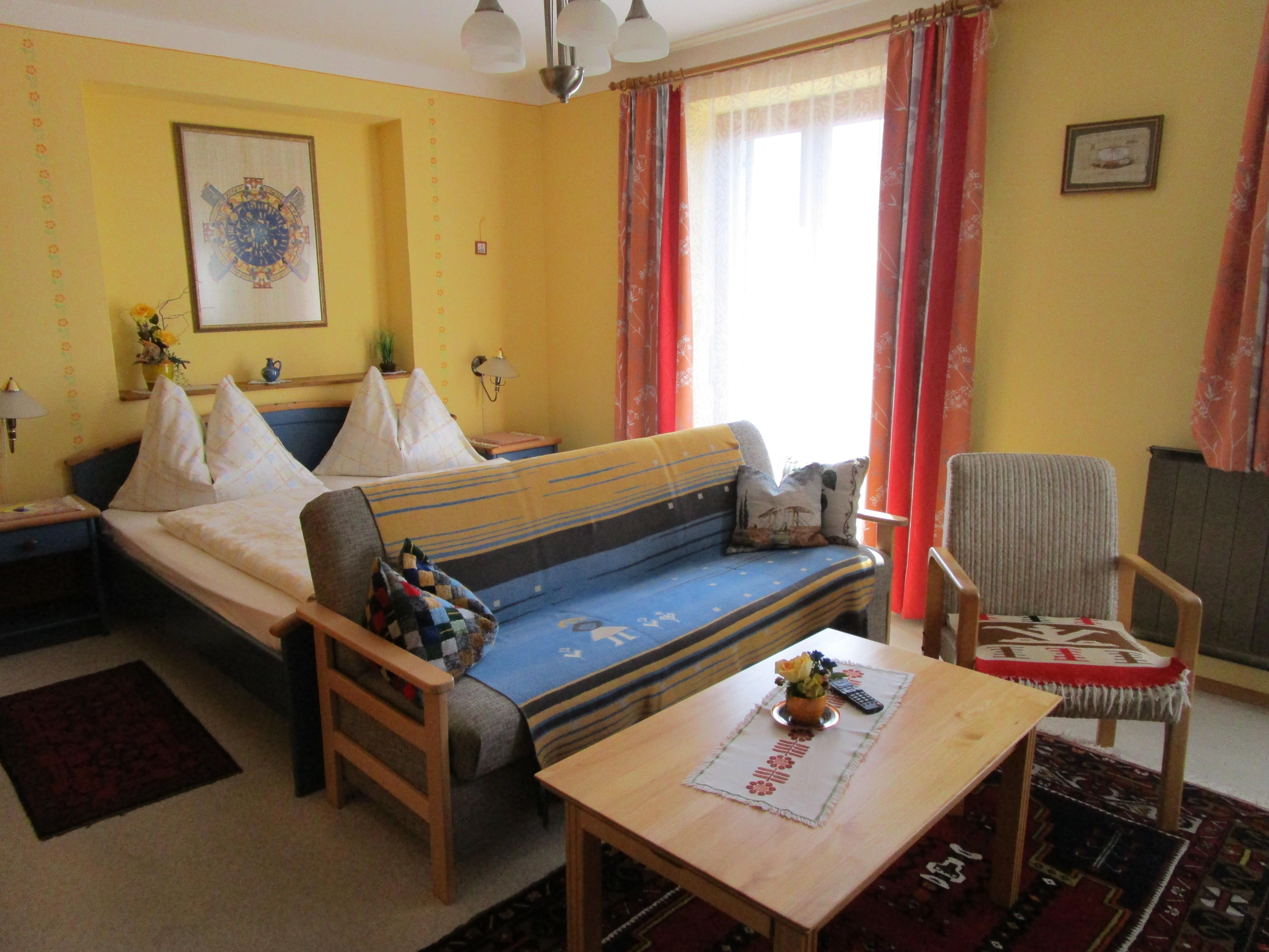 Pokoj s manželskou postelí a pohovkou se stolem v popředí