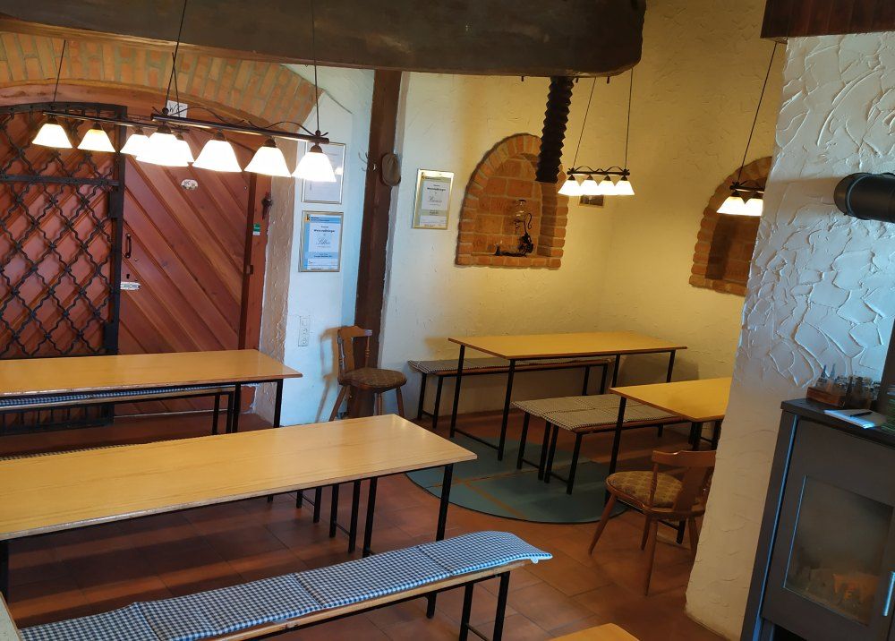 Pohled do interiéru heurigy s dřevěnými stoly, lavicemi a rustikální výzdobou.