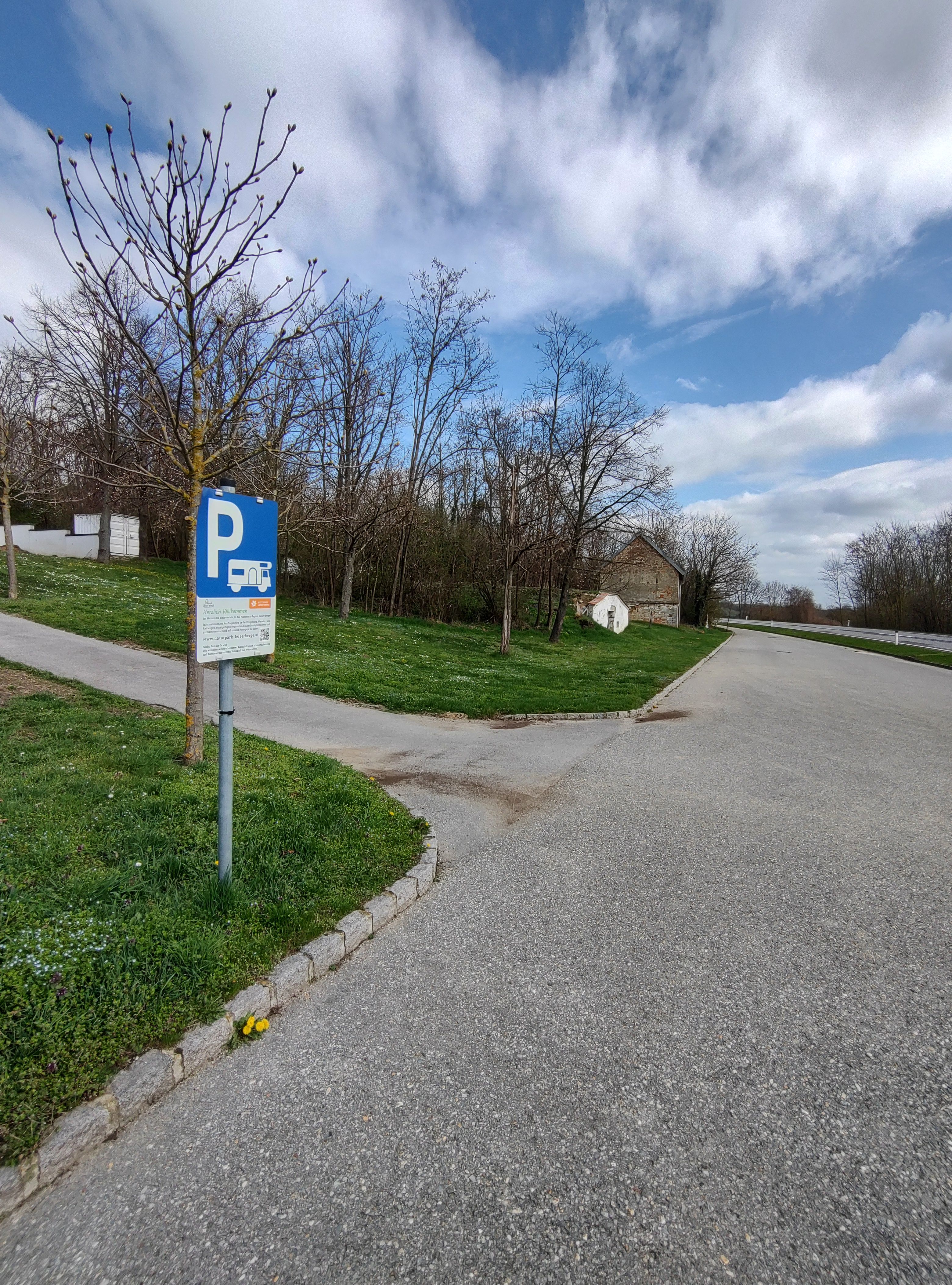 Kemp pro karavany se značkou parkoviště a stromy v pozadí.