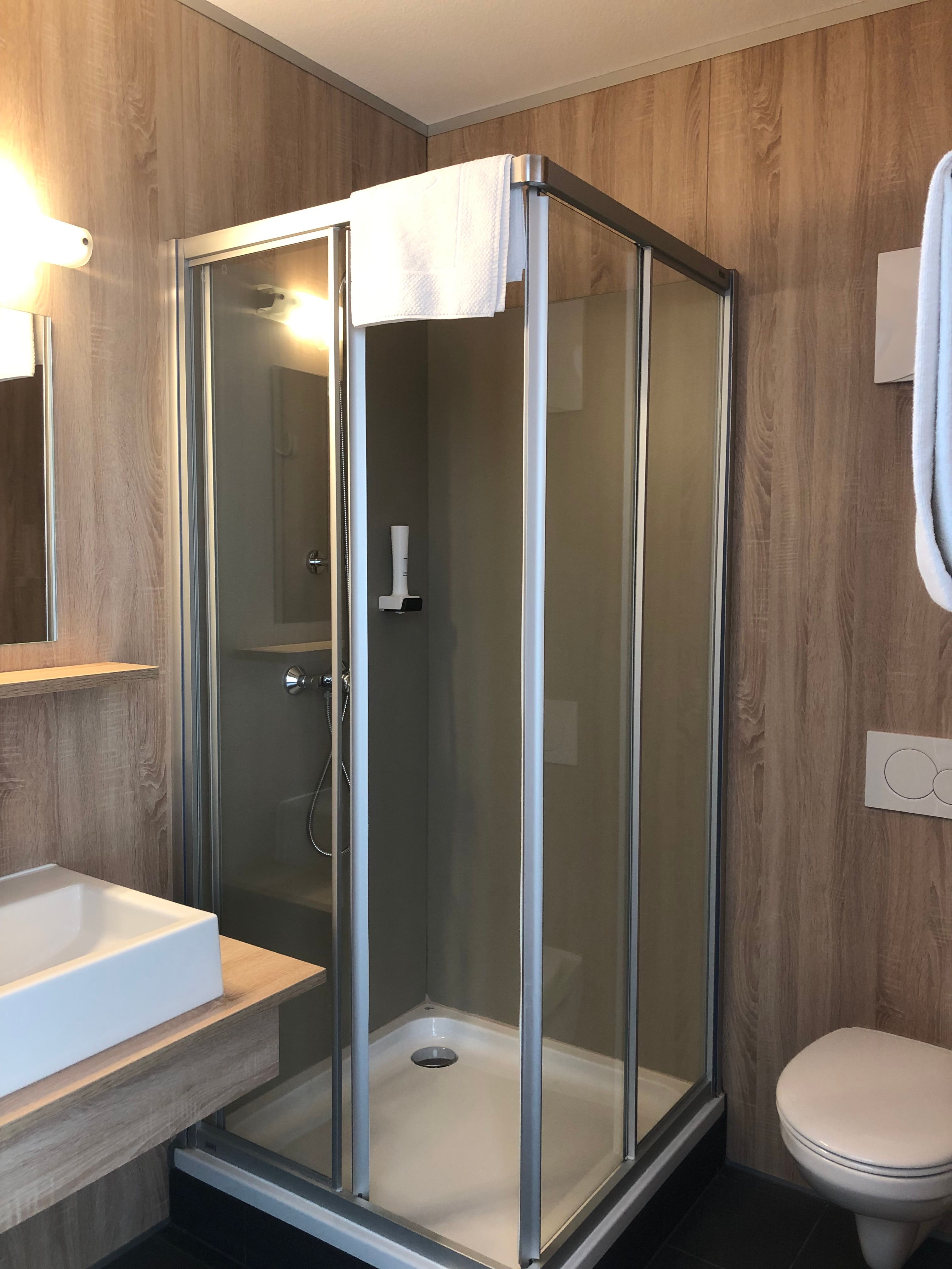 Moderní koupelna se sprchovým koutem, umyvadlem a toaletou.