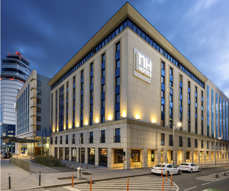 Konferenční centrum NH Vienna Airport za soumraku s osvětlenou budovou.
