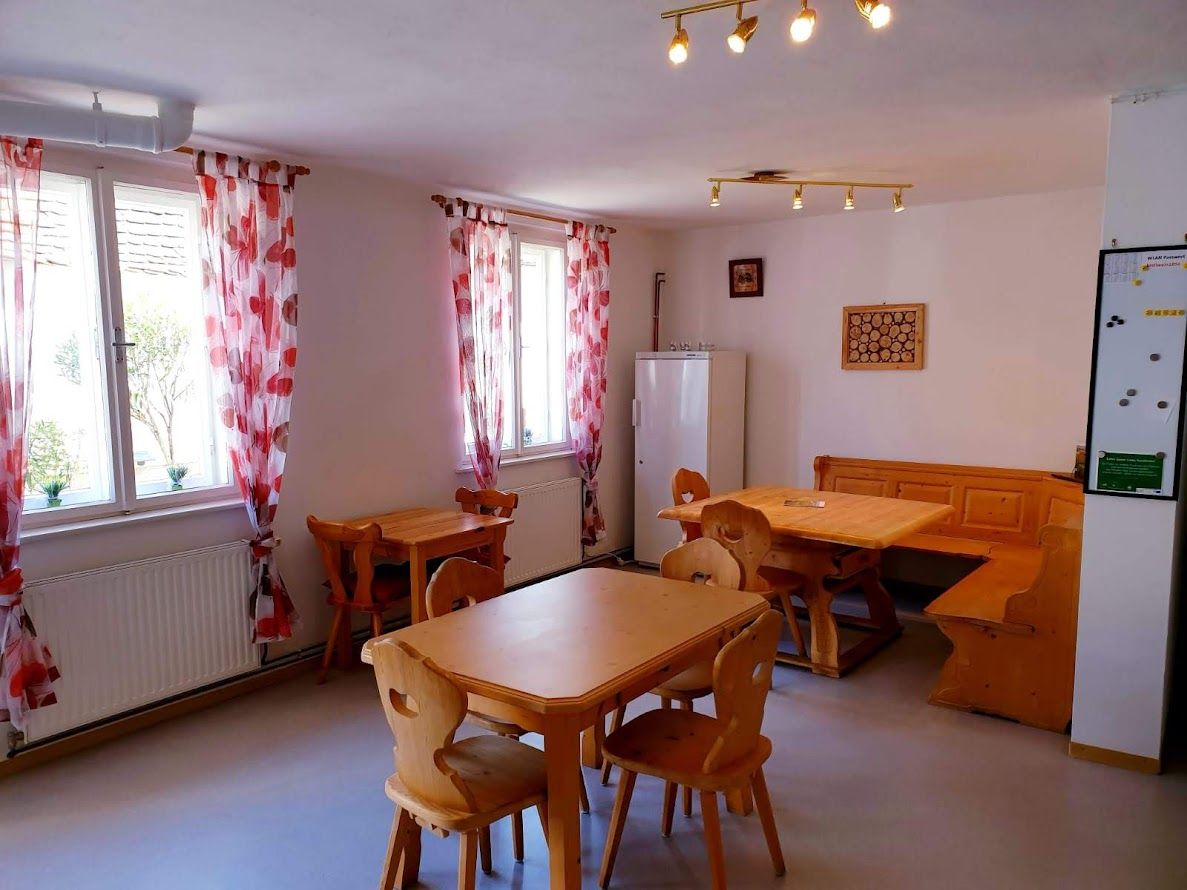 Útulný pokoj s dřevěným nábytkem a červenými závěsy.