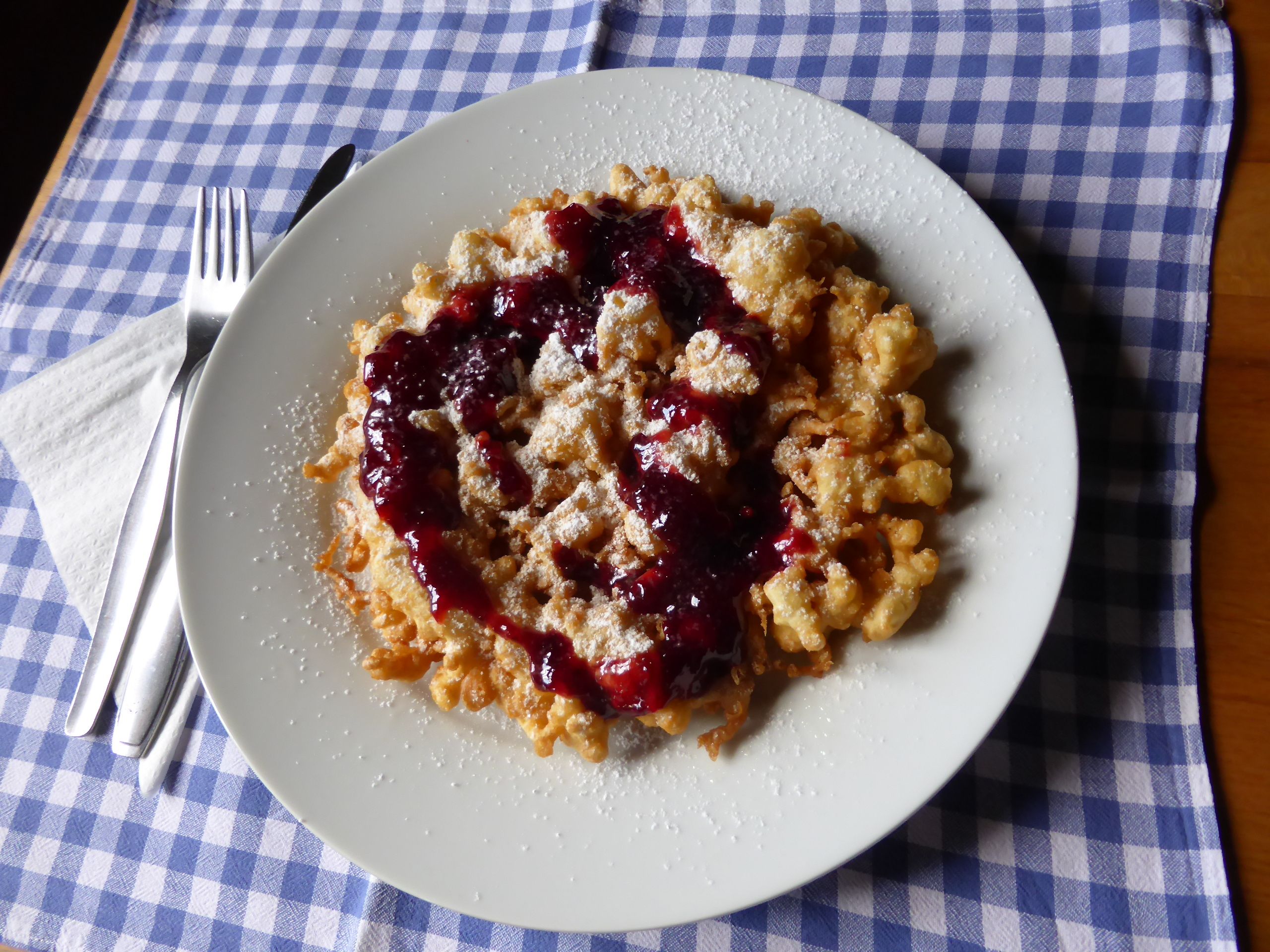 Talíř Kaiserschmarrn a červené ovocné želé na modrobílém kostkovaném plátně.