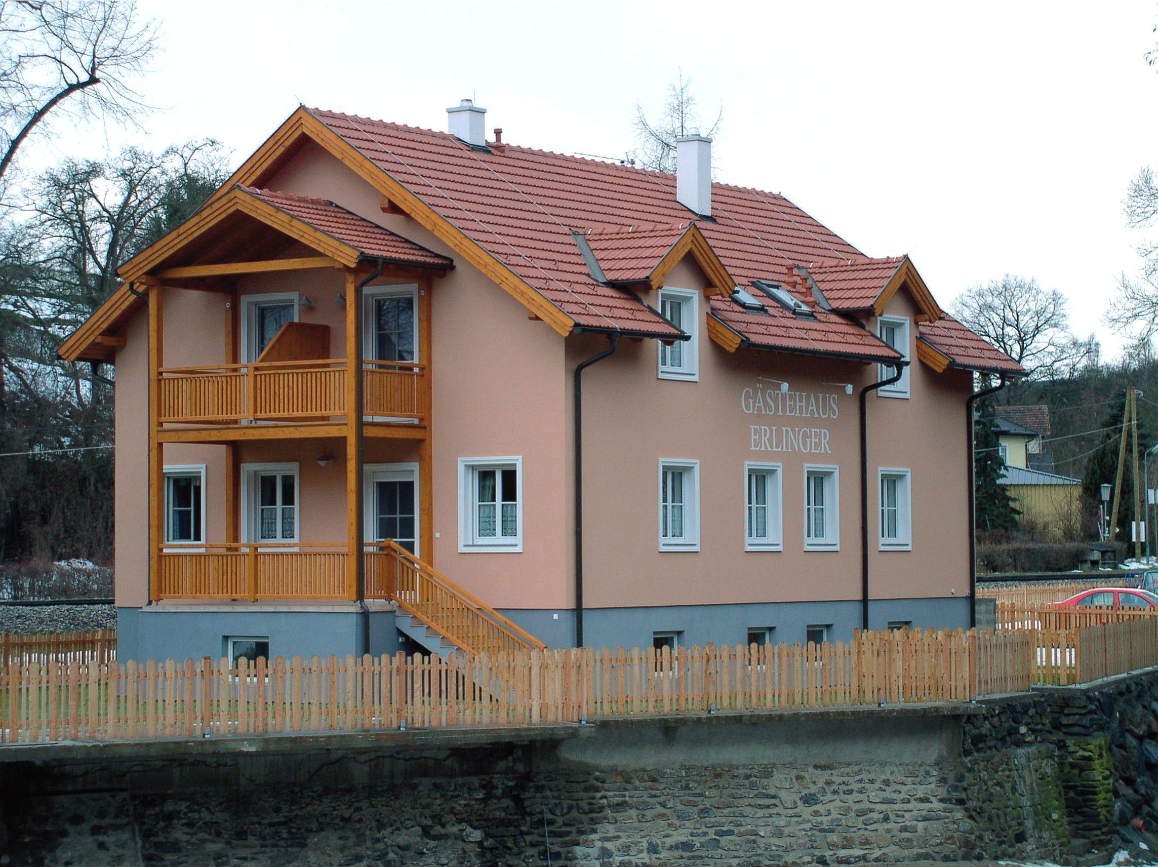Penzion Erlinger s dřevěnou verandou a plotem.