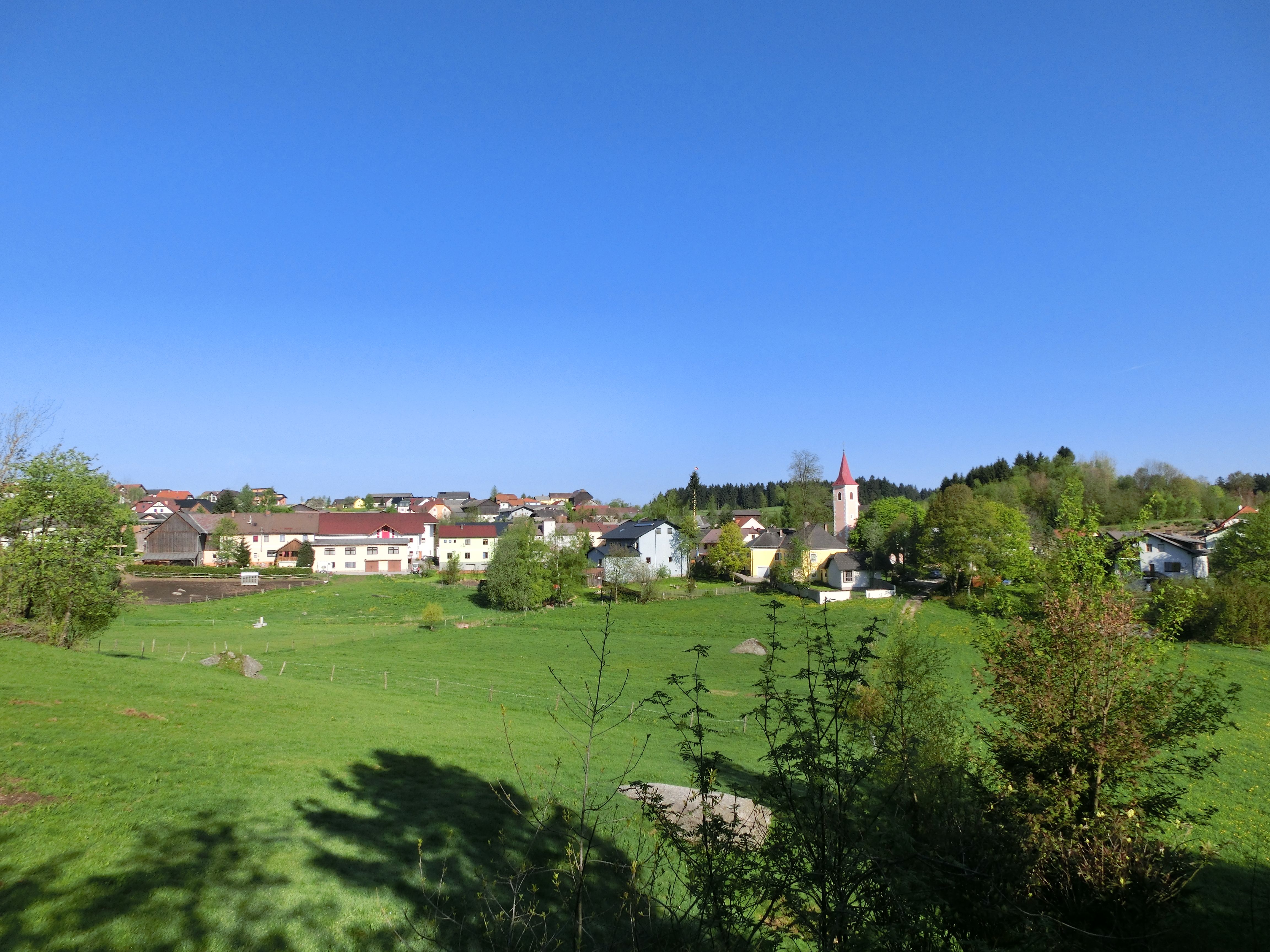 Pohled na krajinu tržního města Altmelon se zelenými loukami a kostelem v pozadí.