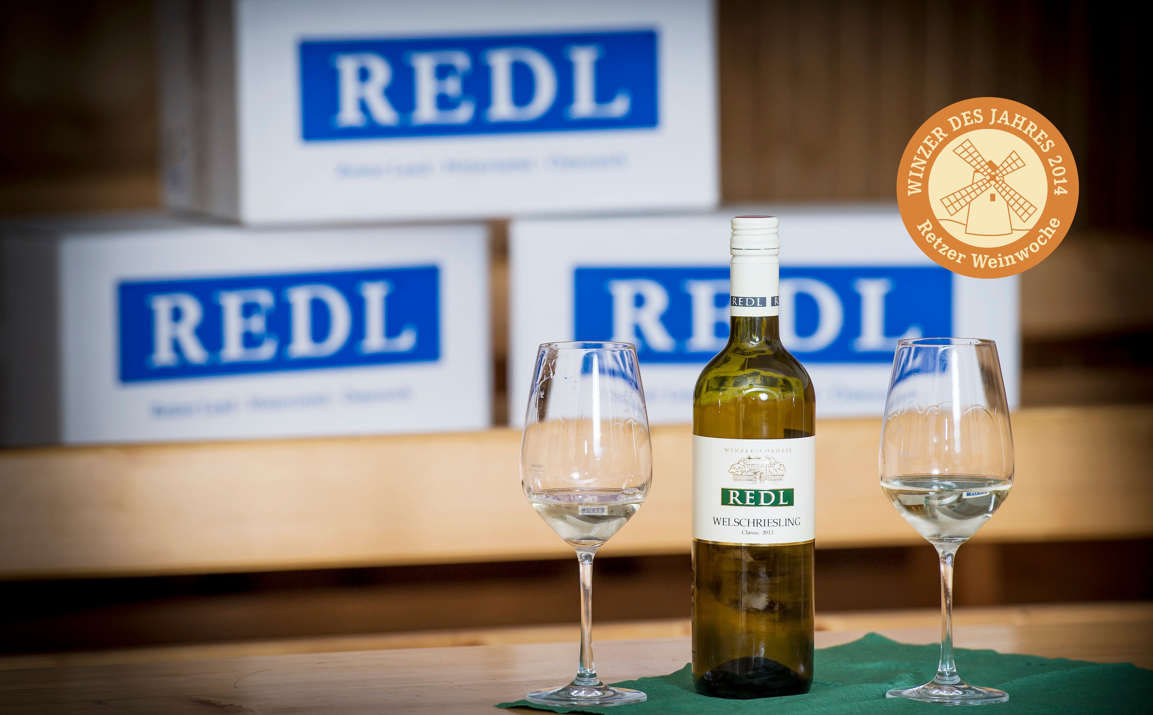 Láhev vína a sklenice před kartony Redl.