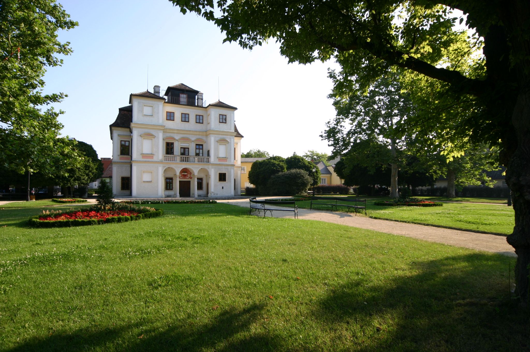 Hotel Belvedereschlössl ve Stockerau je obklopen udržovanou zahradou se stromy a květinovými záhony.