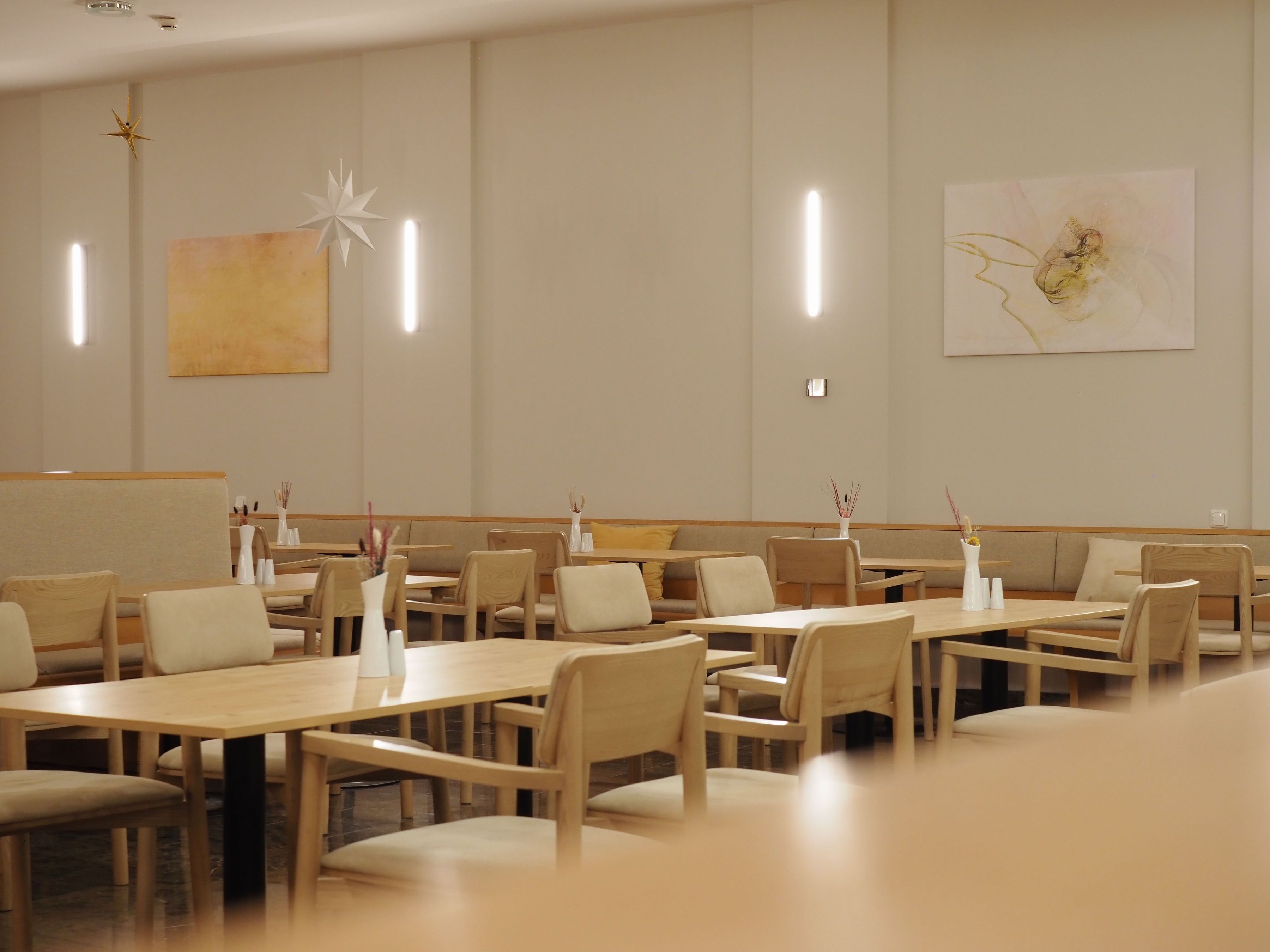Pohled do interiéru moderní restaurace s dřevěným nábytkem a minimalistickou výzdobou.