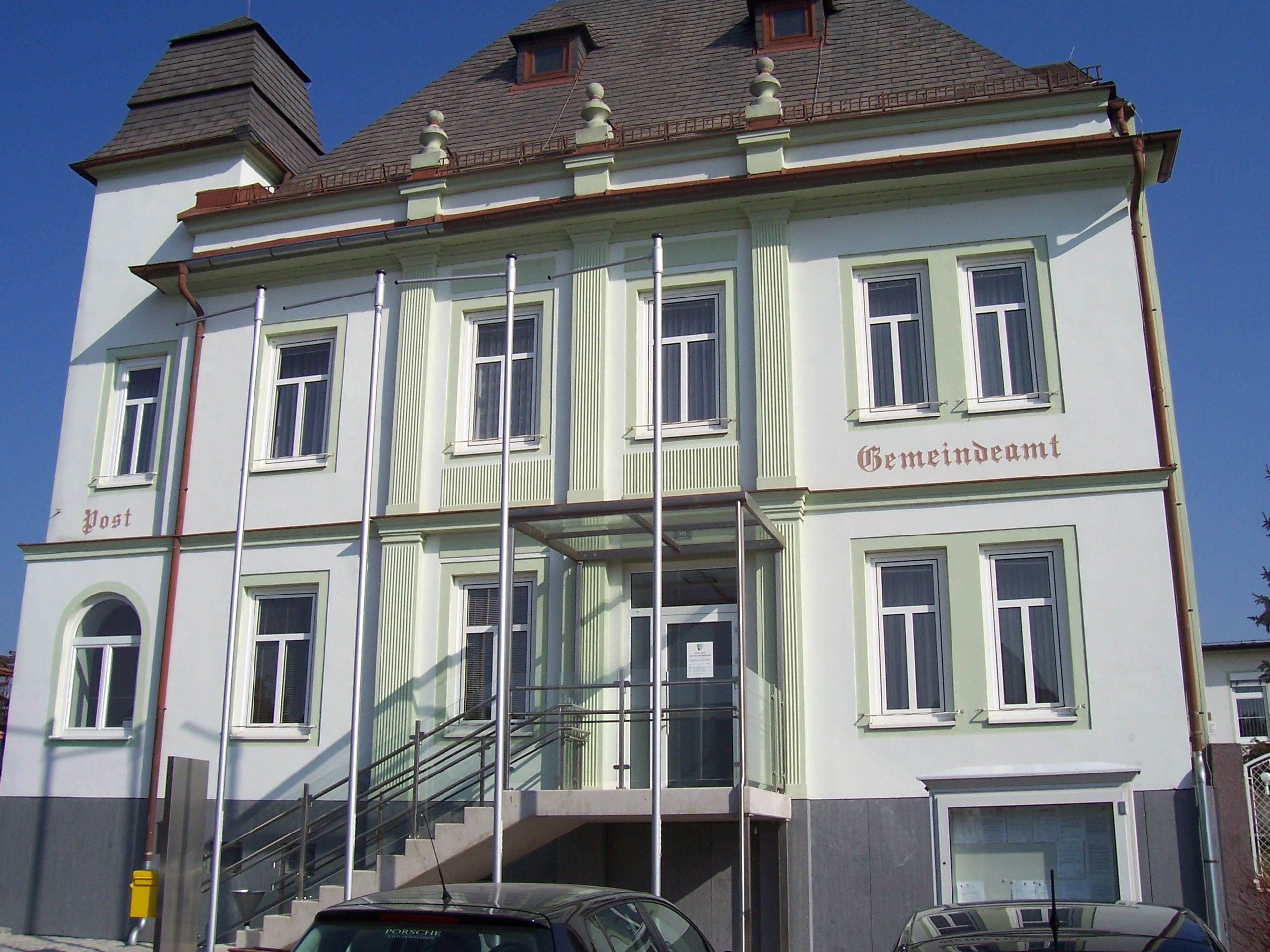 Obecní úřad Untersiebenbrunn se schody a stožáry před budovou.