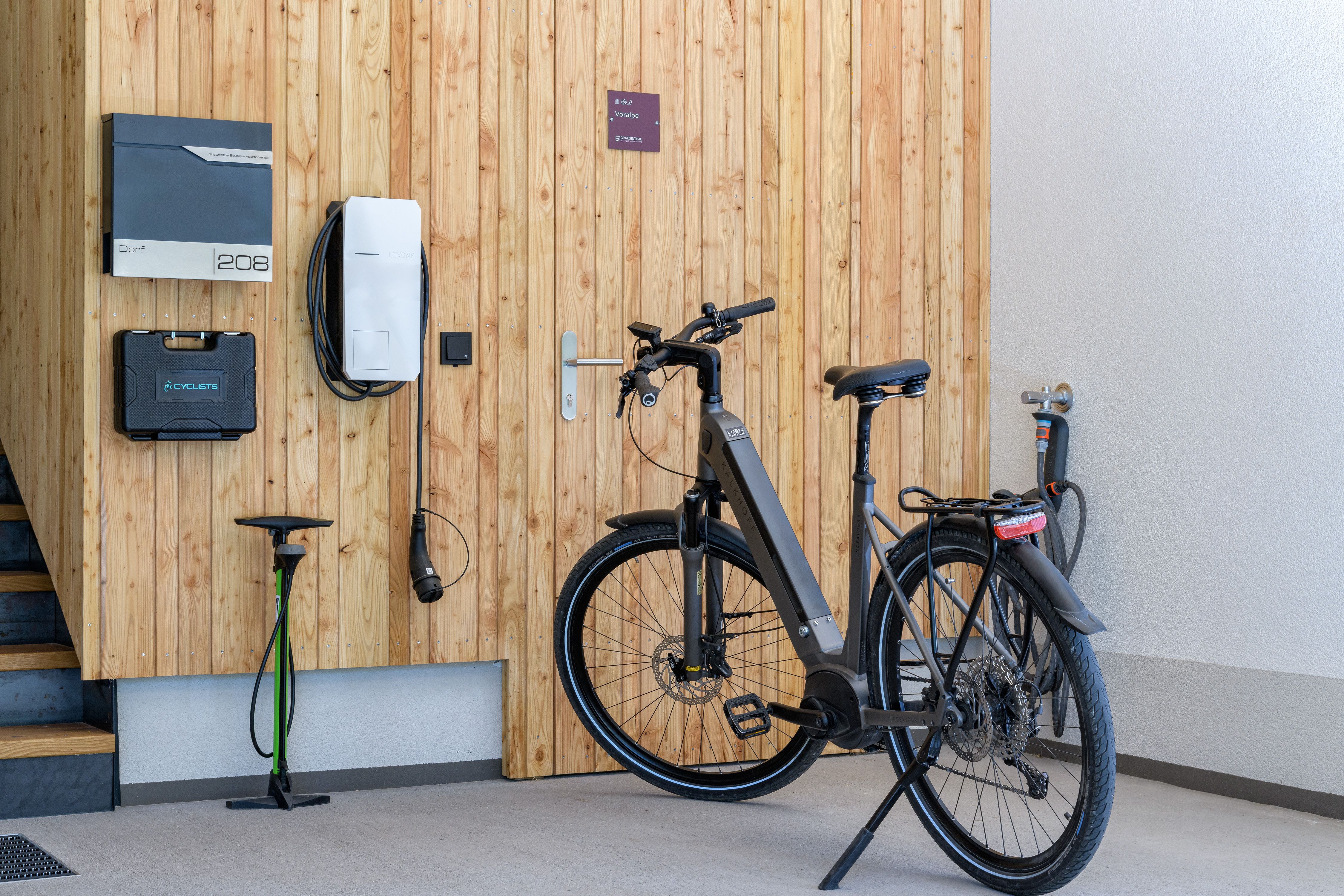 V garáži stojí moderní elektrokolo vedle nabíjecí stanice u dřevěné stěny.