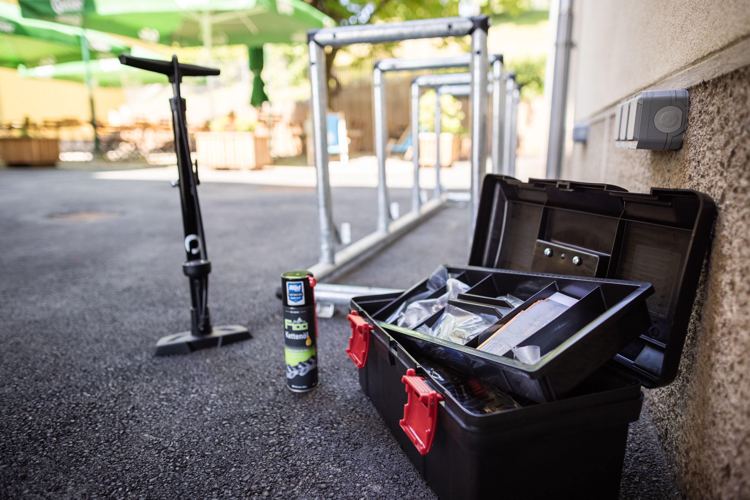 Nářadí na kola, olej na řetěz a pumpička vedle venkovních stojanů na kola.