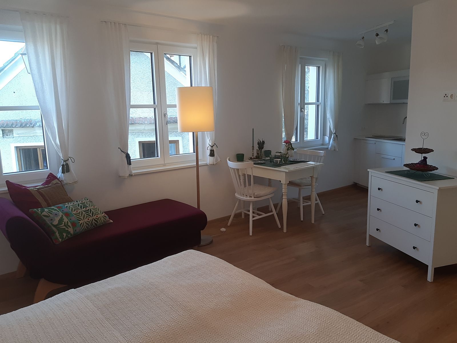 Světlý byt s pohovkou, jídelním stolem a kuchyňským koutem.