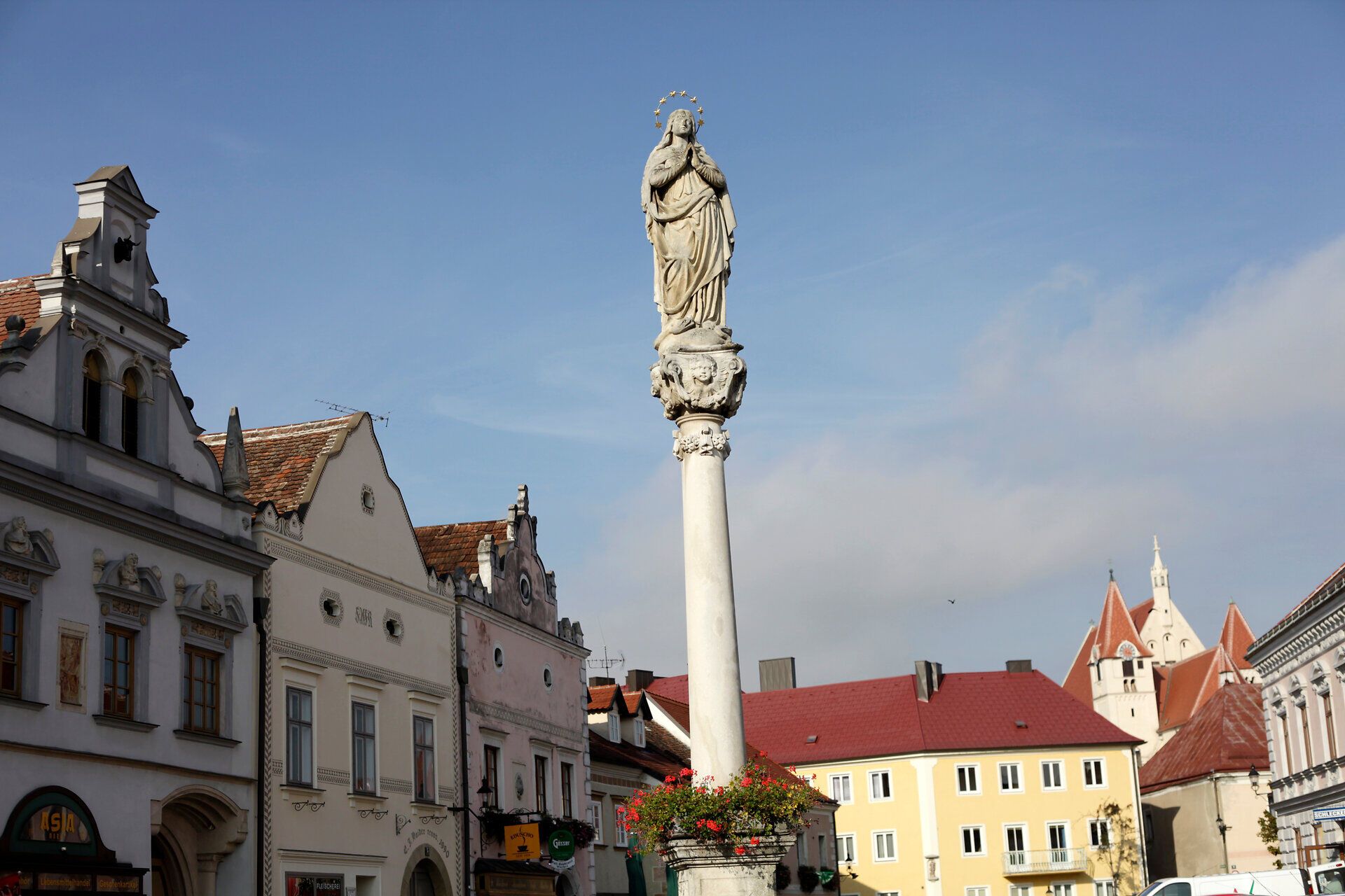 Socha na sloupu v Eggenburgu s historickými budovami v pozadí.