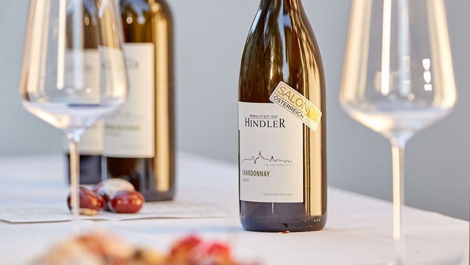 Láhve a sklenice s vínem na stole, vinařství Hindler.