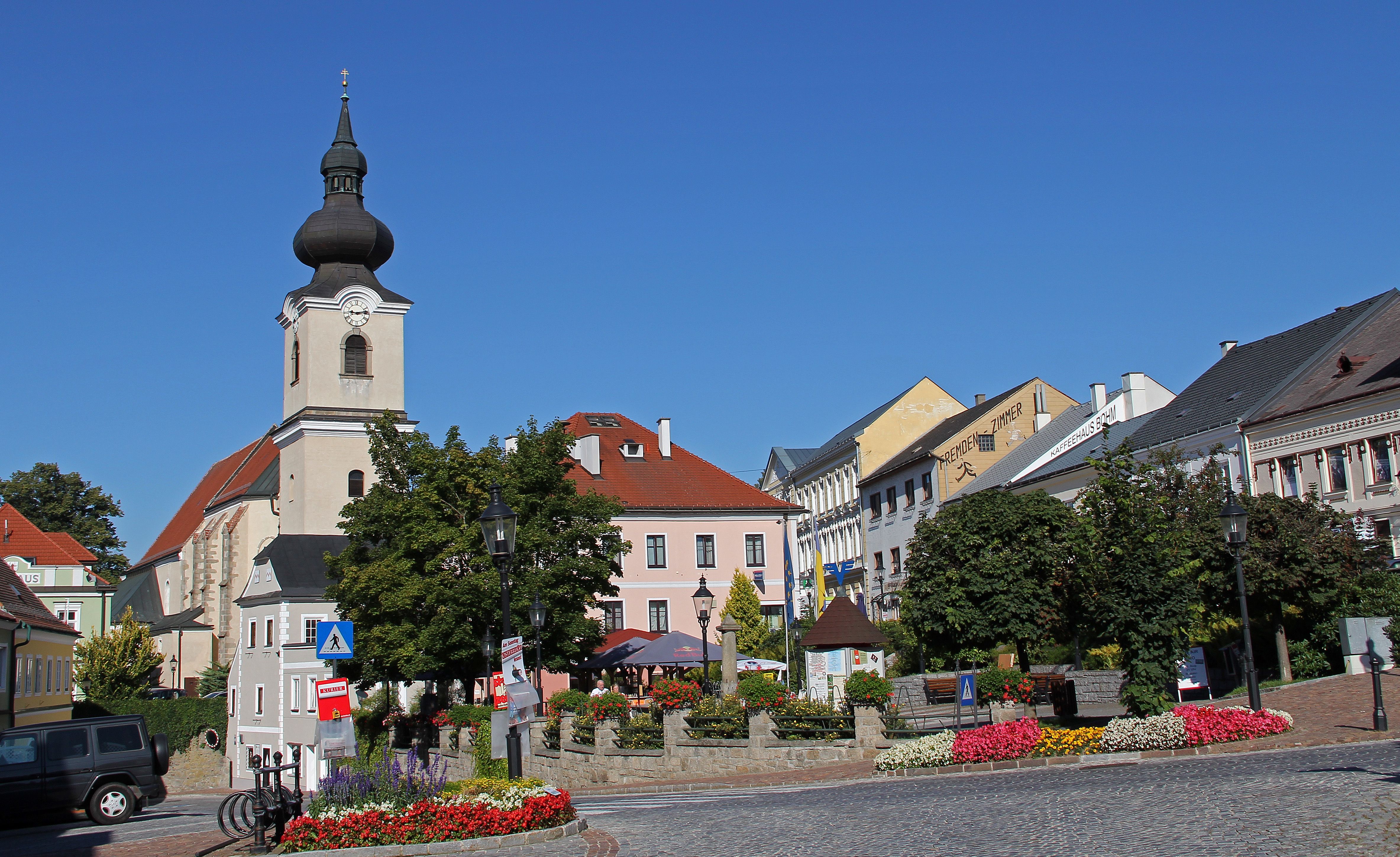 Náměstí v Heidenreichsteinu s kostelem a barevnými květinovými záhony.