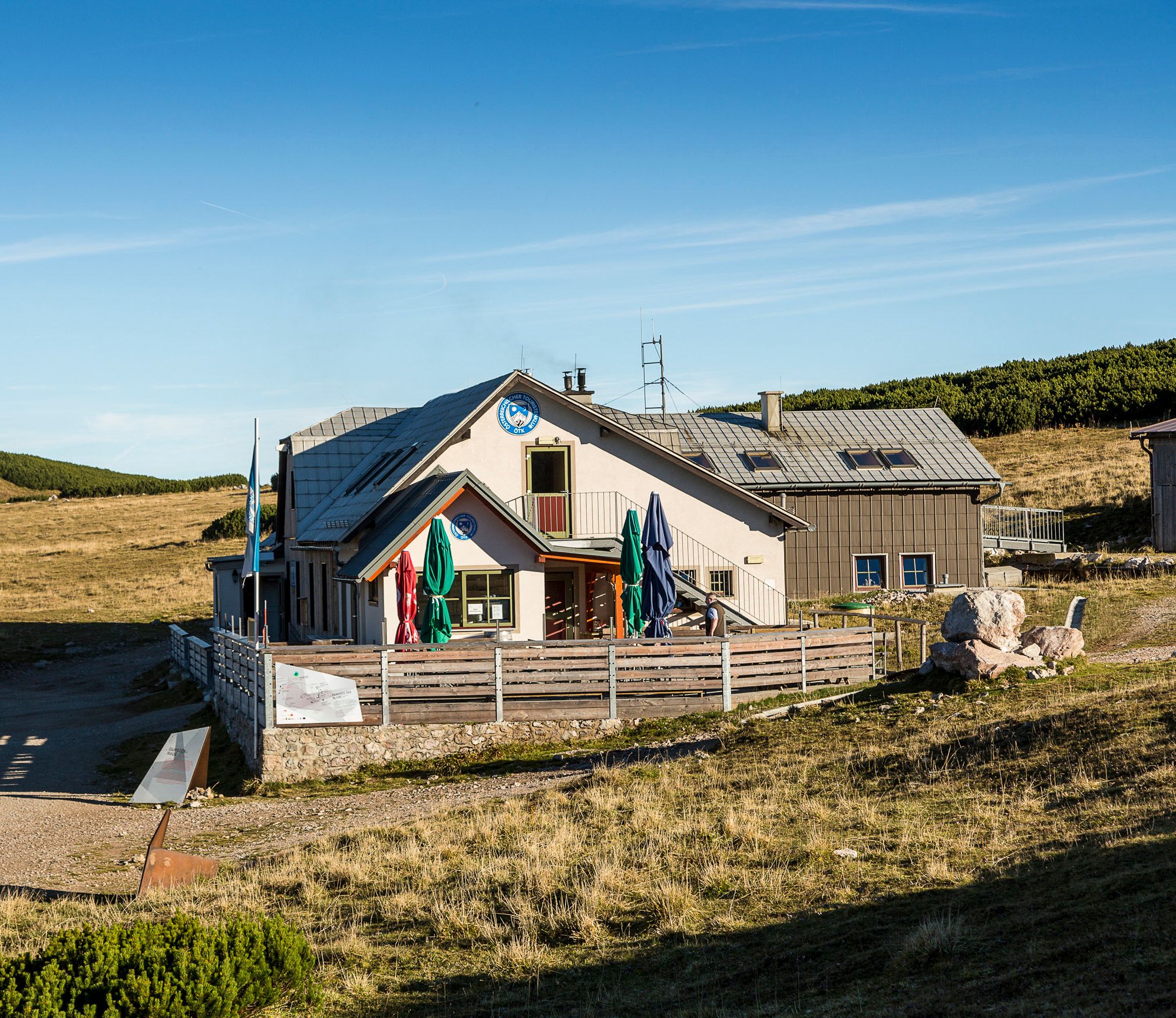 Damböckhaus na hoře Schneeberg ve slunné horské krajině s modrou oblohou.