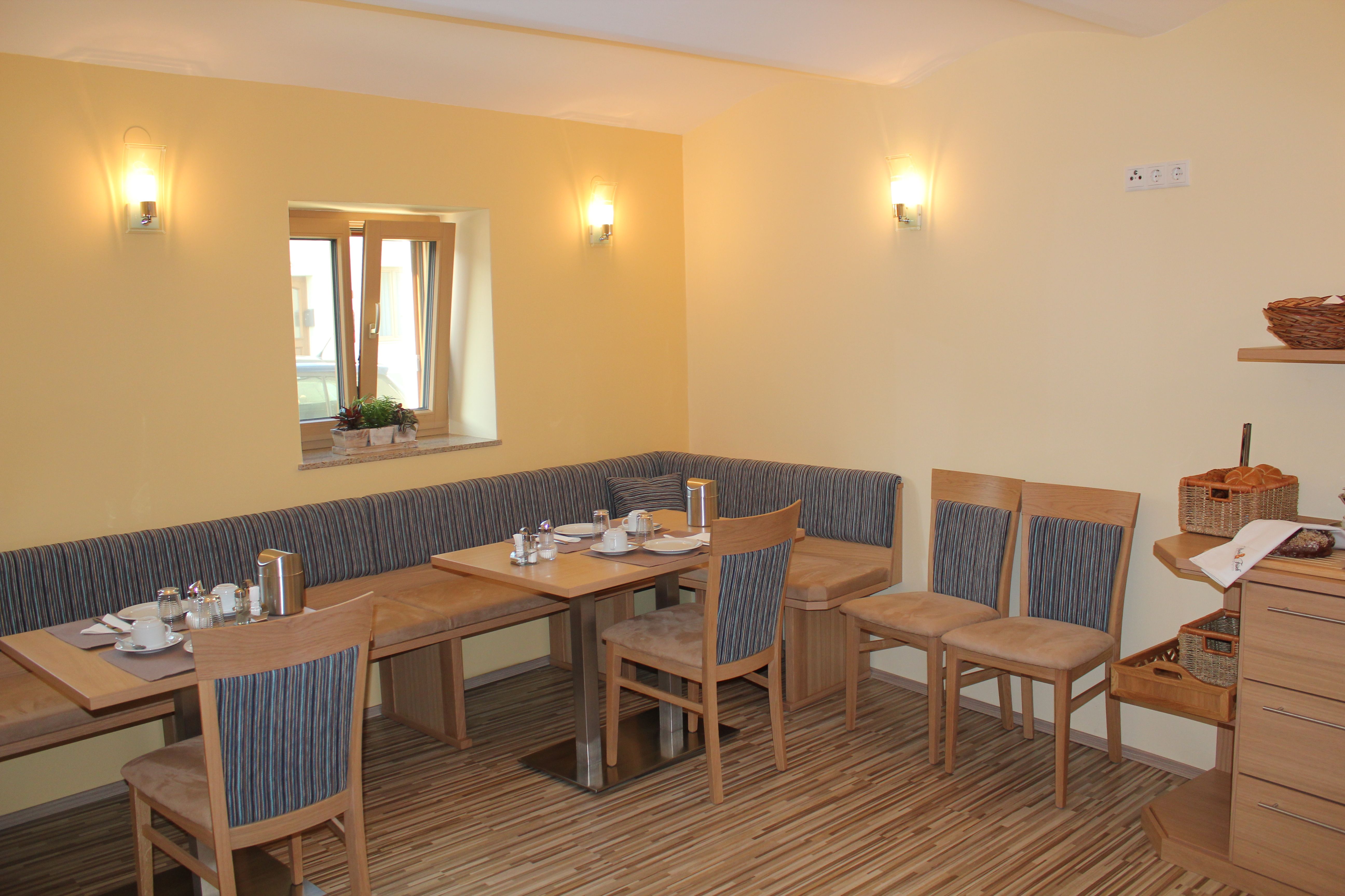 Útulná snídaňová místnost s dřevěným nábytkem a prostíráním.