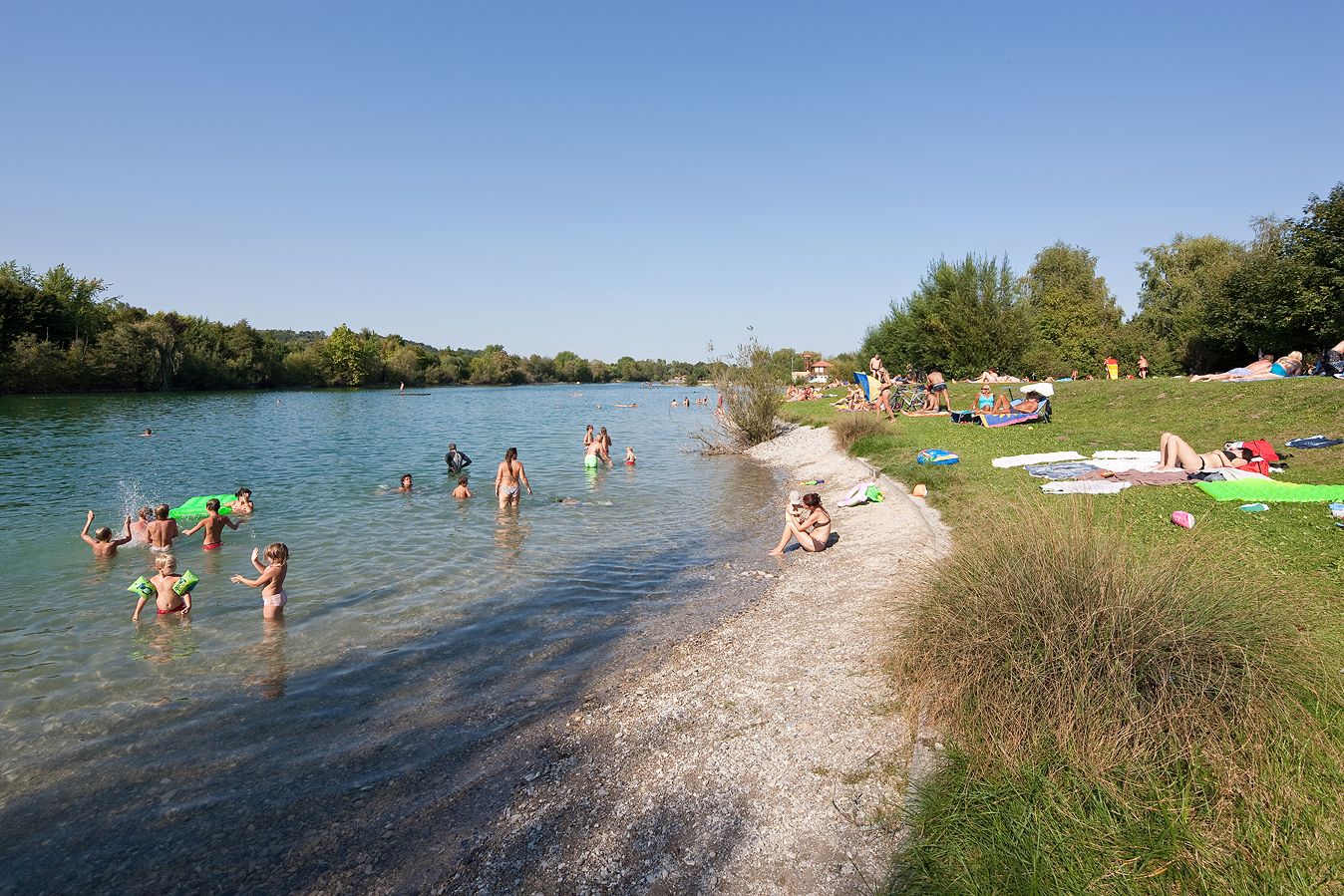 Koupání a odpočinek lidí u jezera Ratzersdorf za slunečného dne.