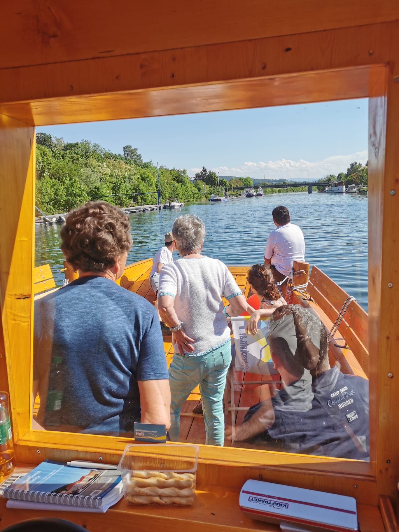 Pohled z lodi na řece s několika lidmi na palubě.