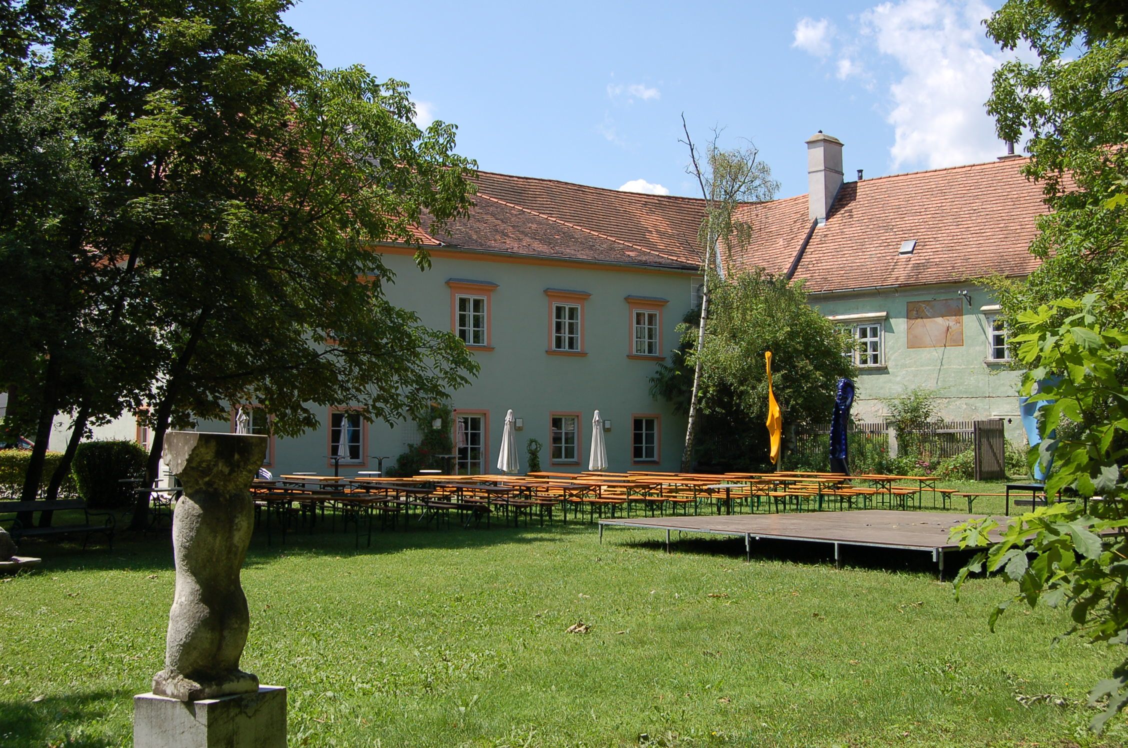 Zámek Bad Fischau se zahradou a pivními stoly.