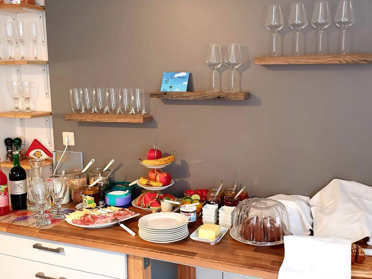 Snídaně formou bufetu se sklenicemi, ovocem, uzeninami a koláči.