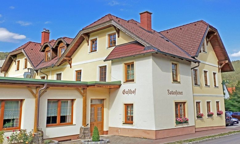 Tradiční hostinec s několika patry a červenými střešními taškami.