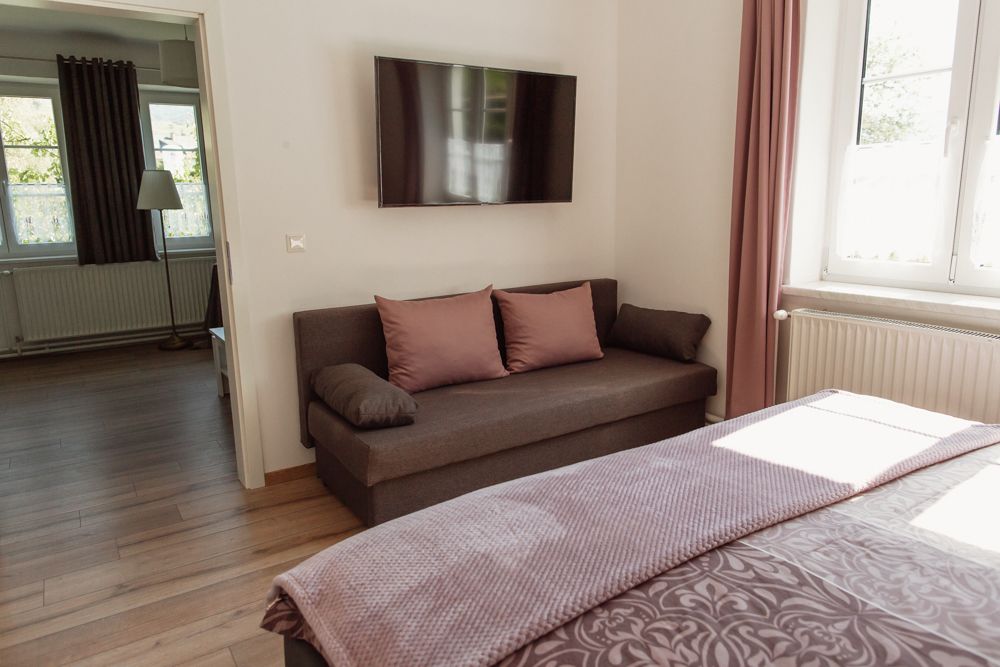 Moderní obývací pokoj s pohovkou, TV s plochou obrazovkou a oknem s růžovými závěsy.