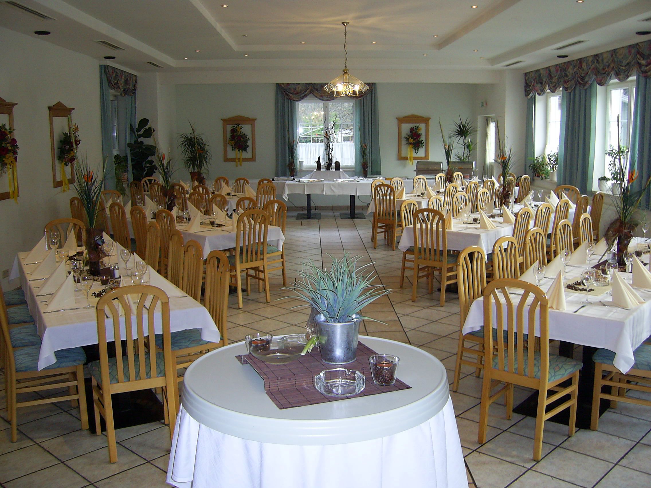 Elegantní jídelna s prostřenými stoly a dřevěnými židlemi.
