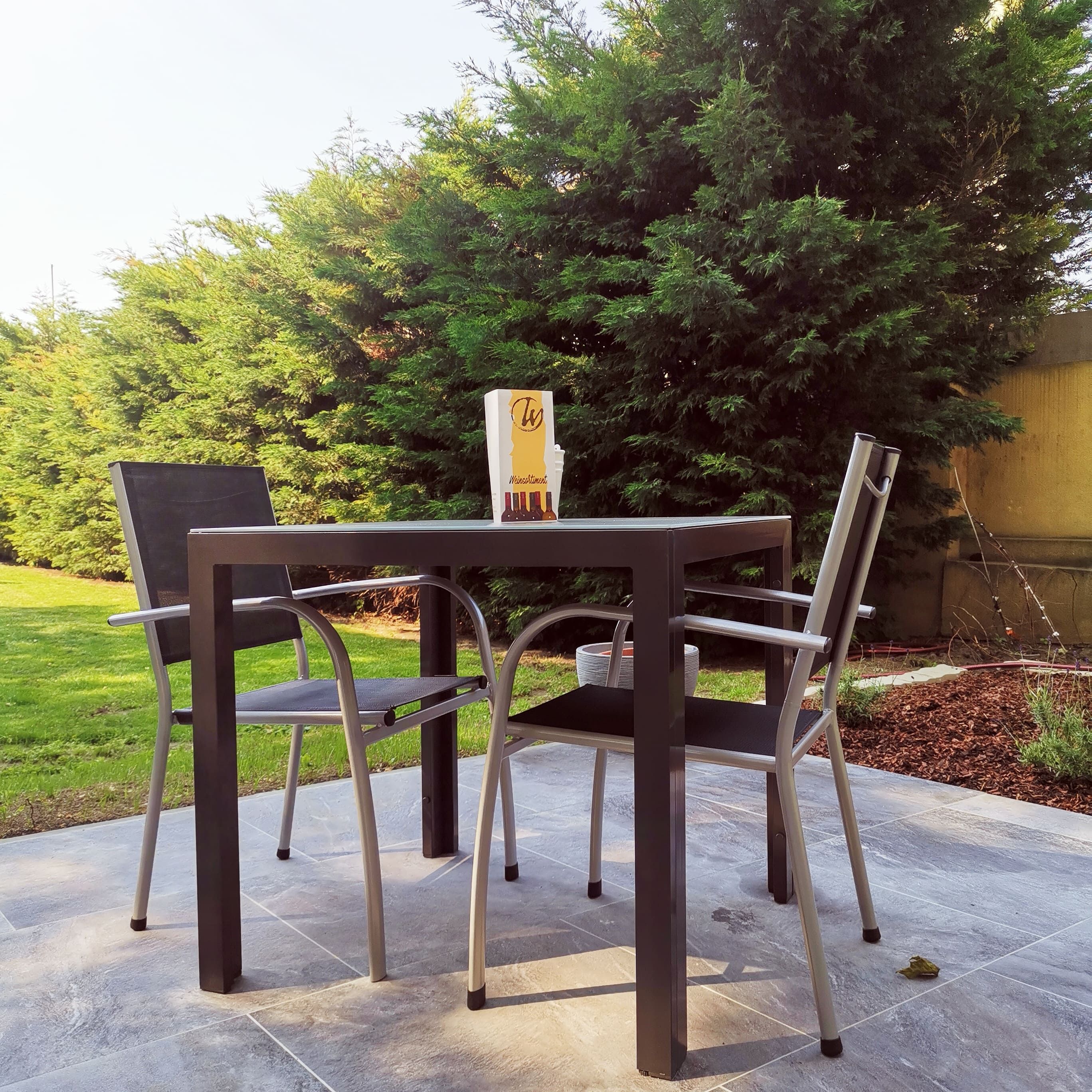 Terasa se stolem, dvěma židlemi a stromy v pozadí.