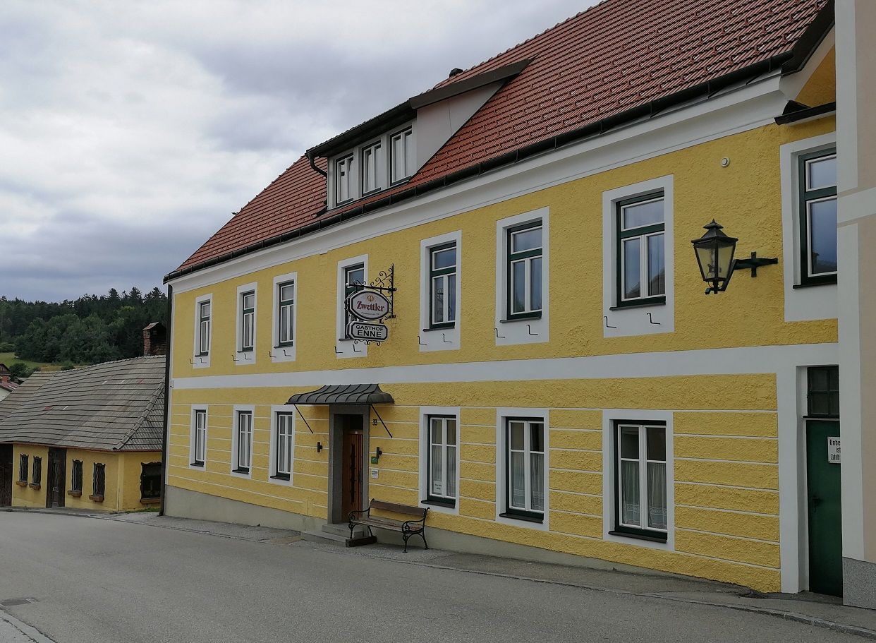 Žlutá budova s nápisem "Gasthof Enne" a nápisem Zwettler.