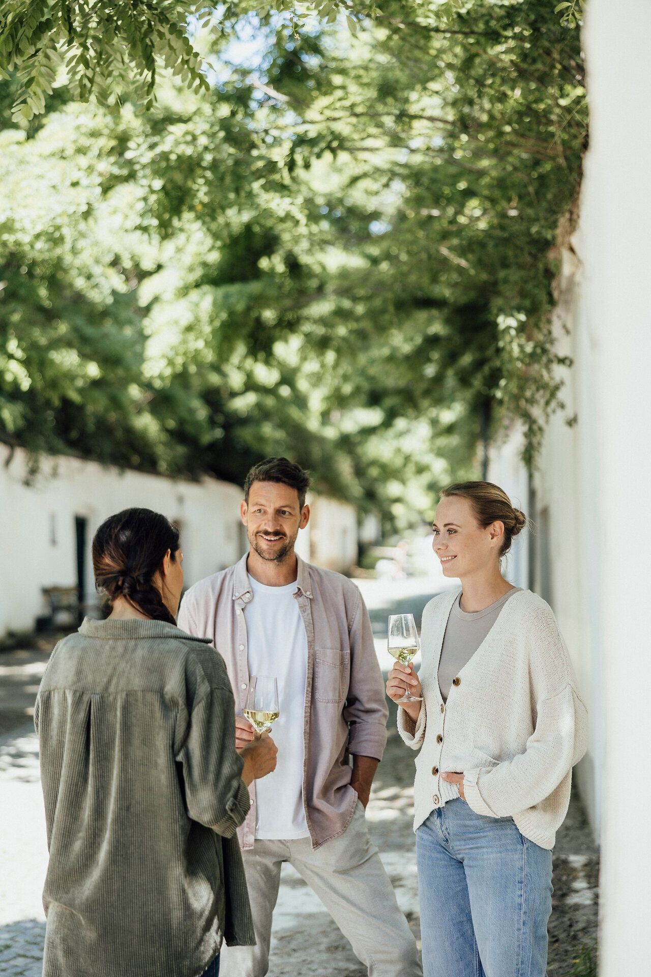 In der malerischen Kellergasse genießen Freunde den Frühling mit einem Glas Wein in der Hand. Umgeben von üppigem Grün und blühenden Pflanzen, wird hier das Leben gefeiert und auf die schönen Momente angestoßen. Die entspannte Atmosphäre lädt dazu ein, die Seele baumeln zu lassen und die köstlichen Weine der Region zu probieren.