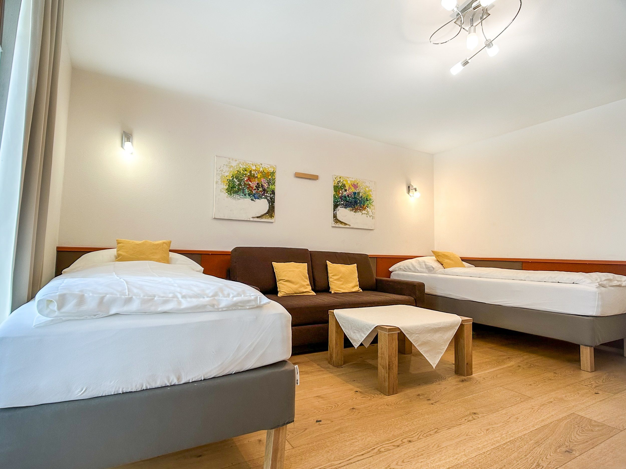 Ložnice se dvěma lůžky, pohovkou a stolem.