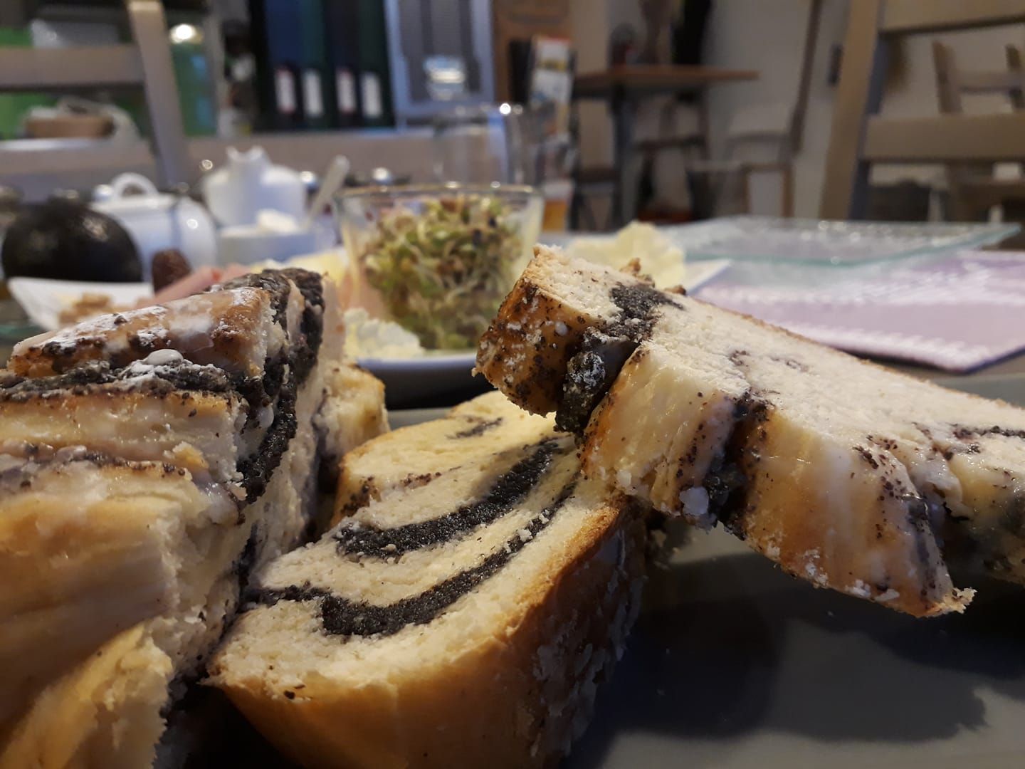 Detailní záběr makového koláče na snídaňovém stole s rozmazaným pozadím.