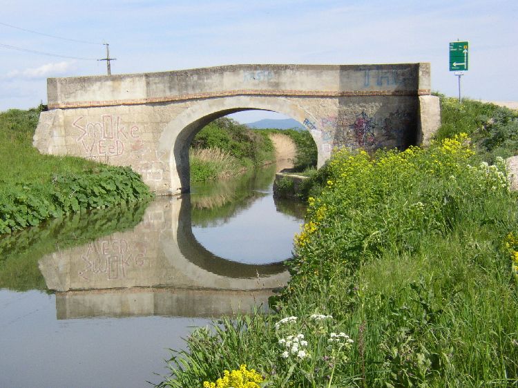 Most přes kanál Wiener Neustadt v Eggendorfu s graffiti a odrazem ve vodě.