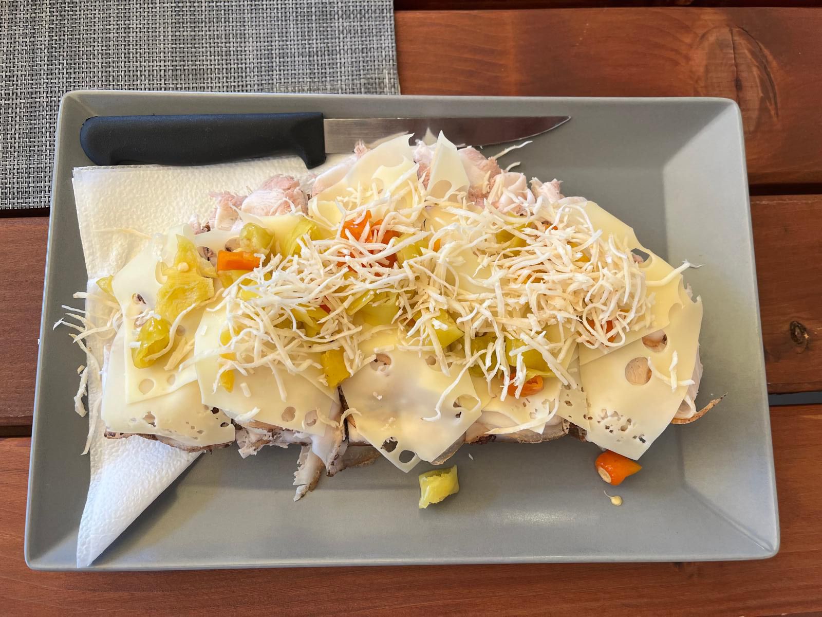 Sýrový sendvič se zeleninou a strouhaným křenem na šedém talíři.