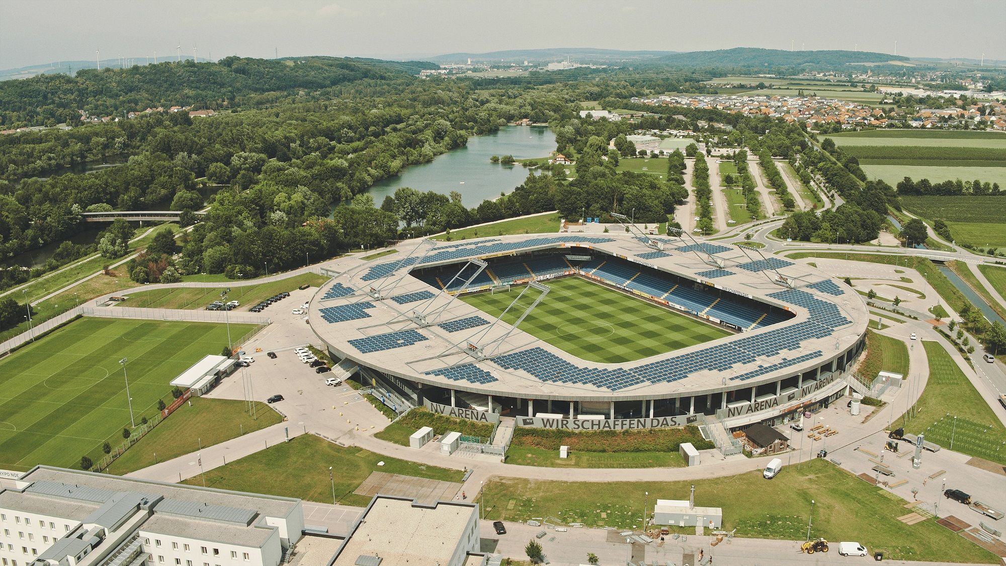 Letecký pohled na NV Arenu v St. Pöltenu, obklopenou zelenou krajinou a řekou.