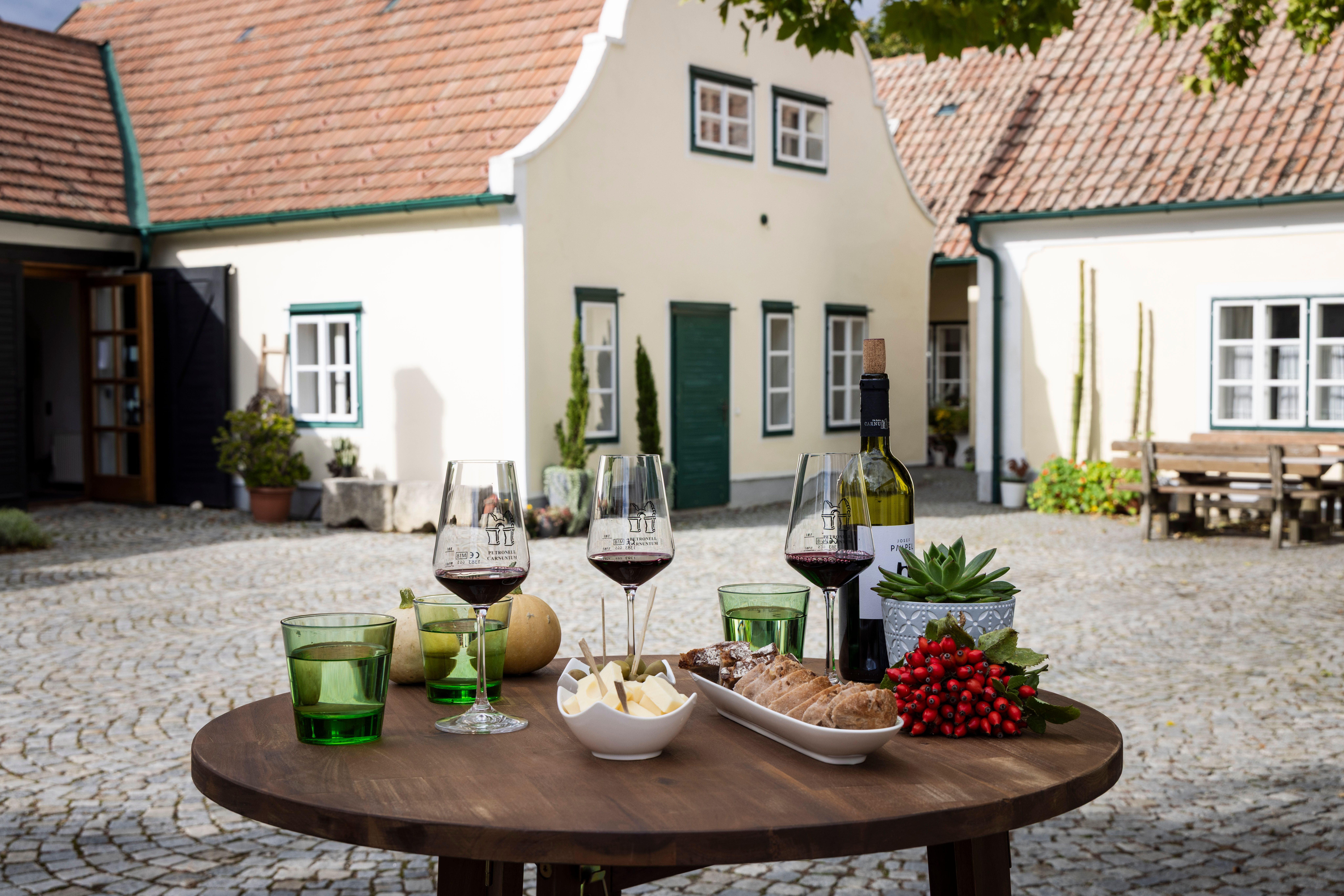 Stůl se sklenicemi na víno, sýrem a chlebem ve vinařství na nádvoří