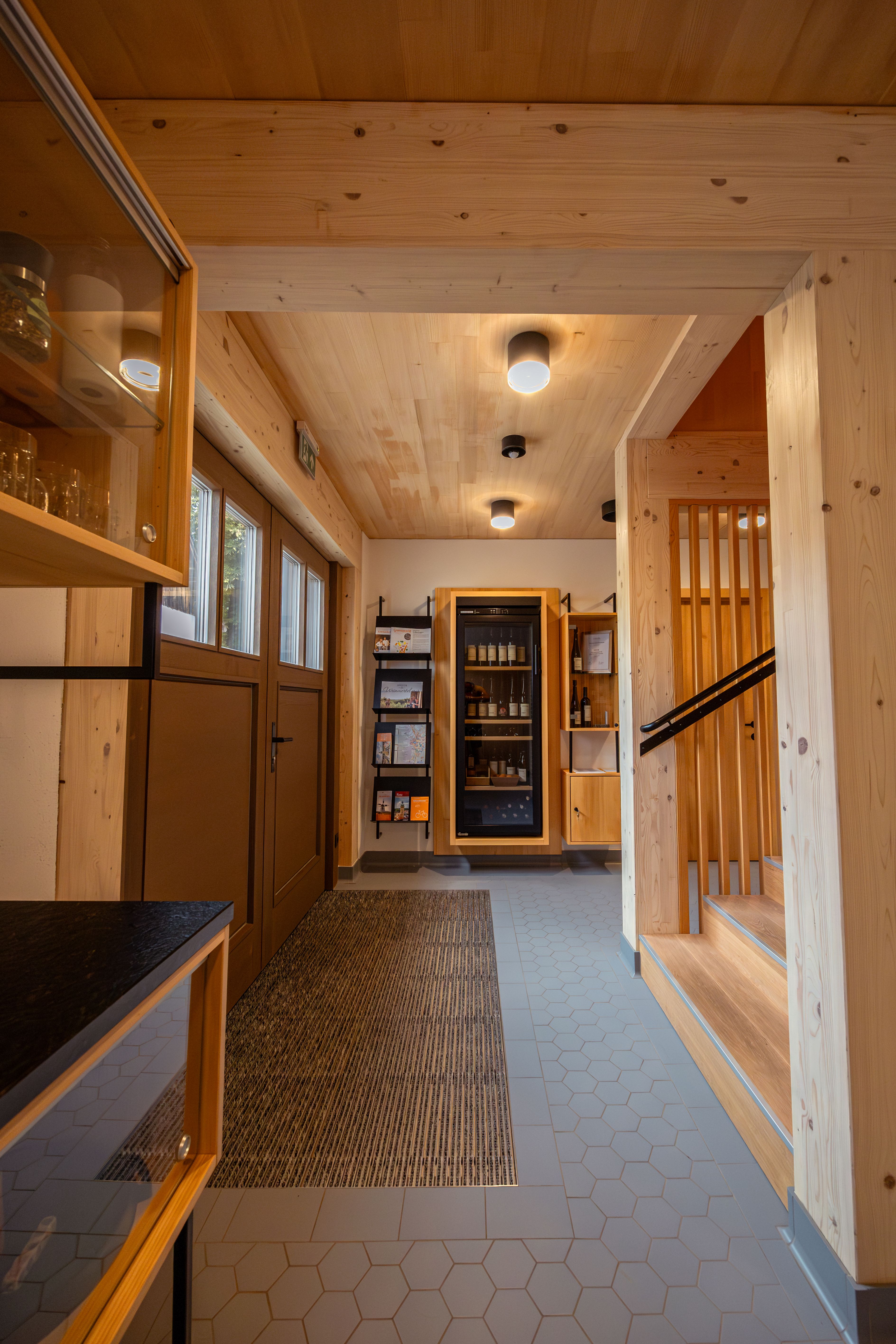 Moderní sklep ve Weinviertelu za soumraku, obklopený vinnou révou a zahradou. Nápis "Dovolená na statku".