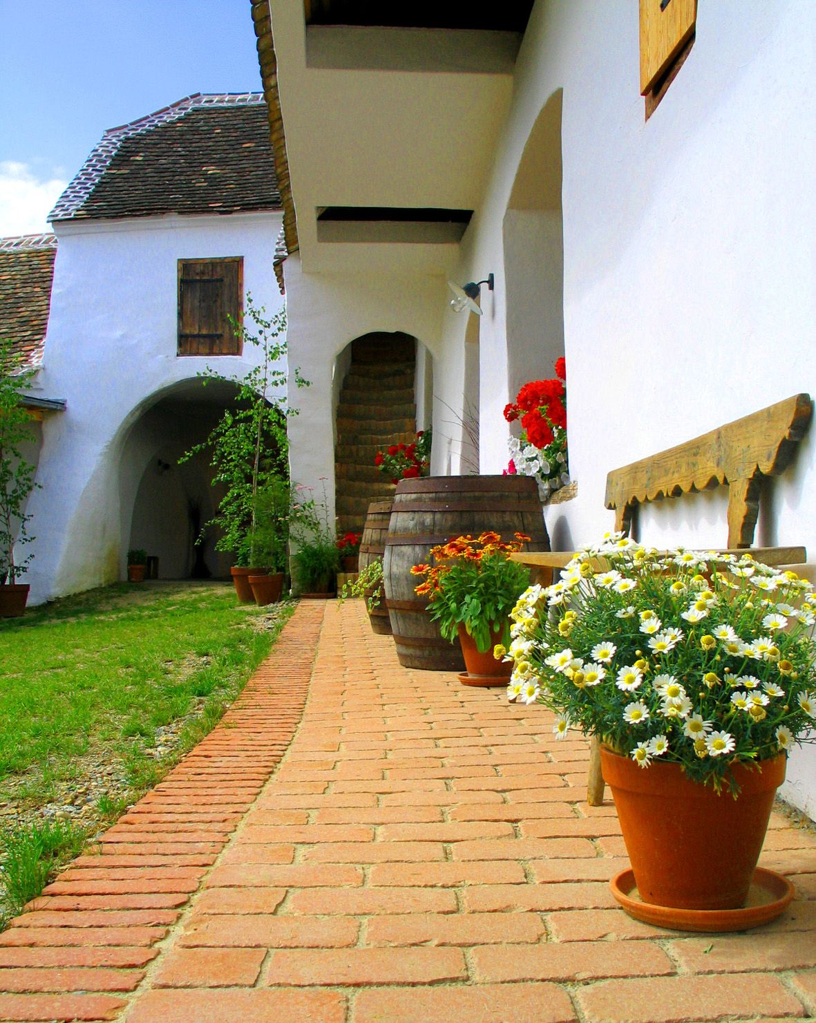 Tradiční nádvoří s květinami a dřevěnými sudy.
