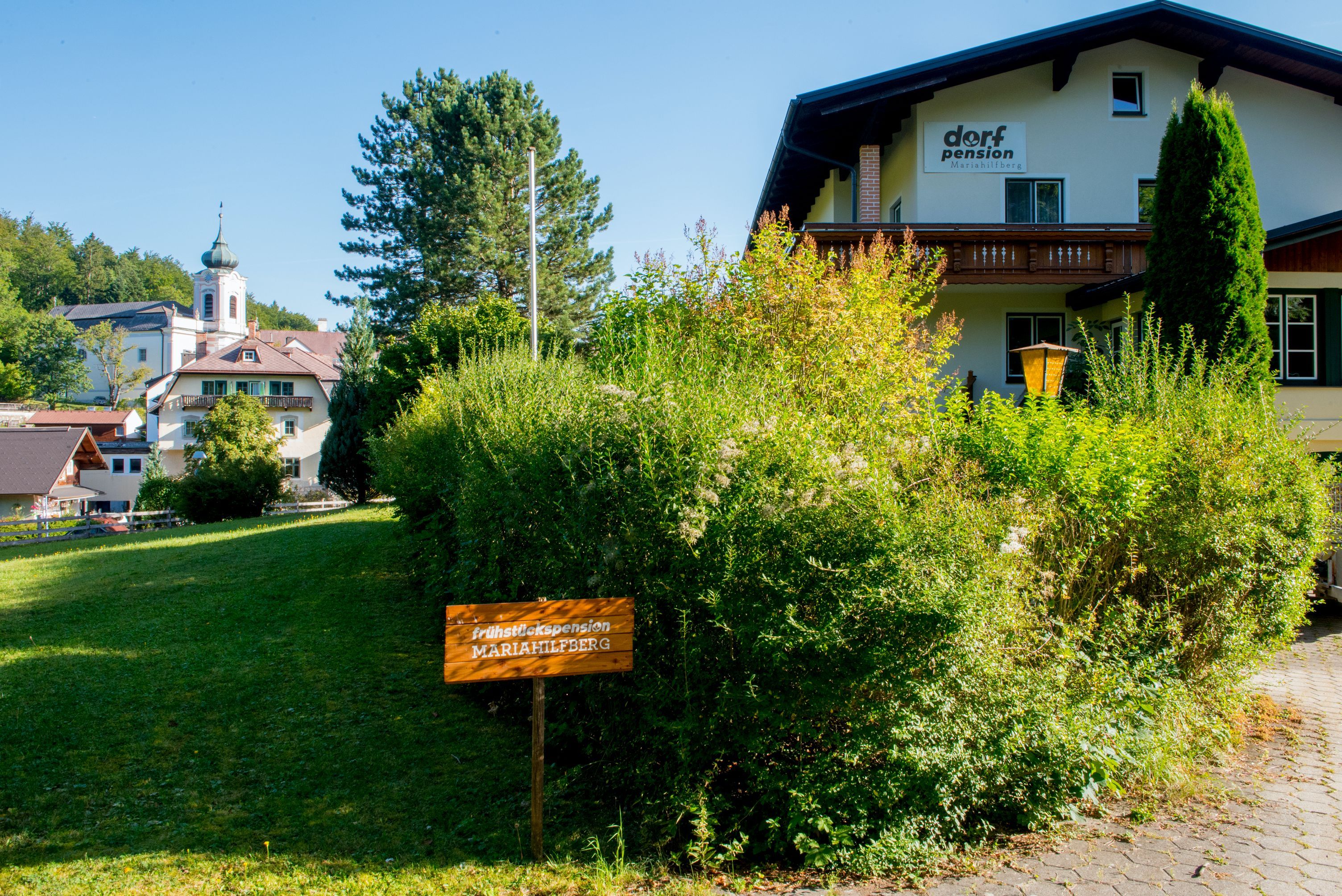 Budova s označením "Dorfpension" a nápisem "Frühstückspension Mariahilfberg" v zeleni.