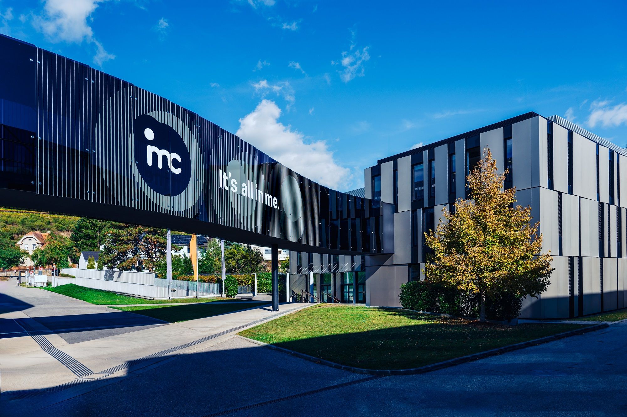 Moderní budova IMC Krems se skleněným mostem a nápisem "It's all in me".