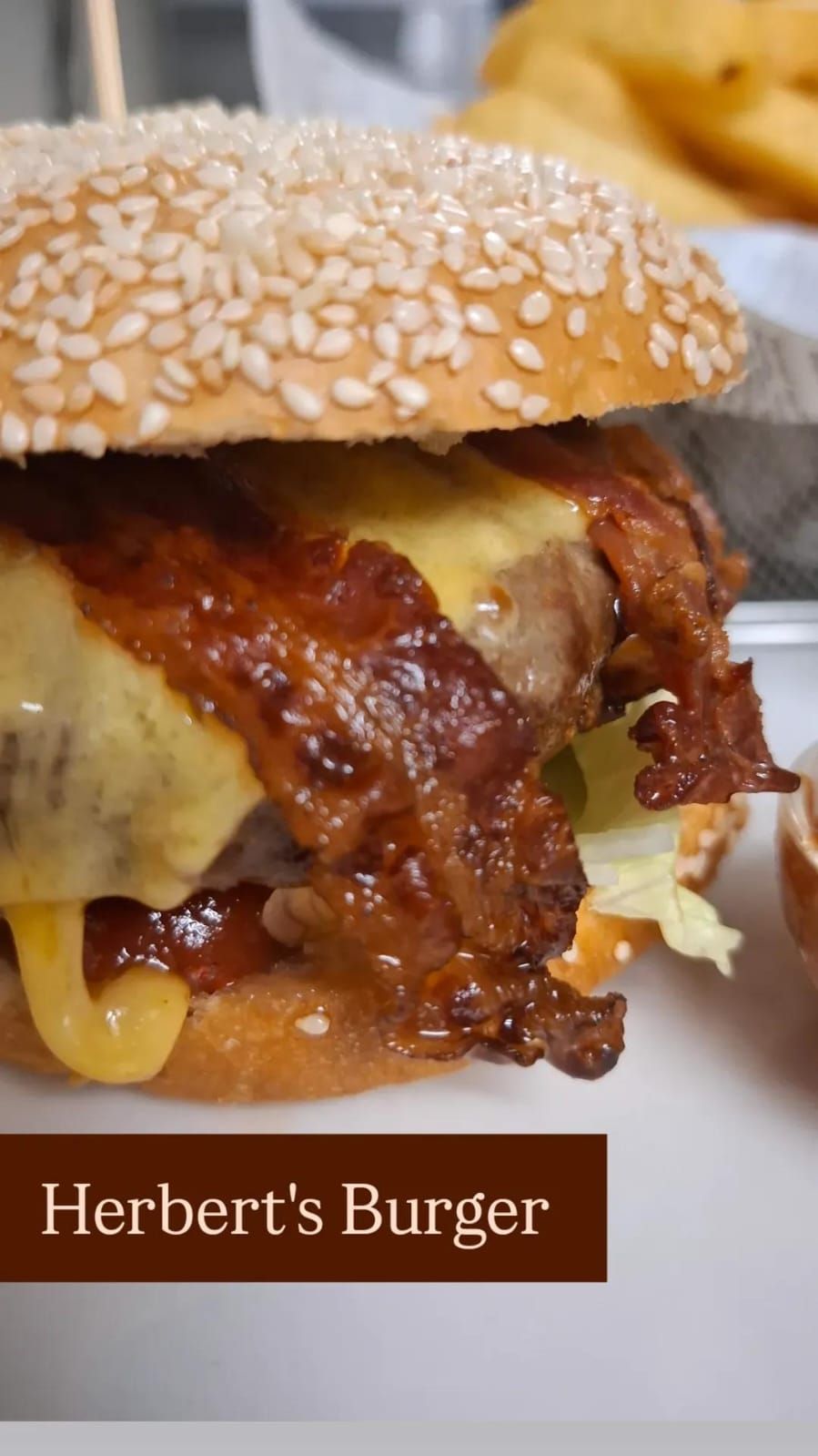 Detailní záběr hamburgeru se sezamovou houskou, taveným sýrem a křupavou slaninou.