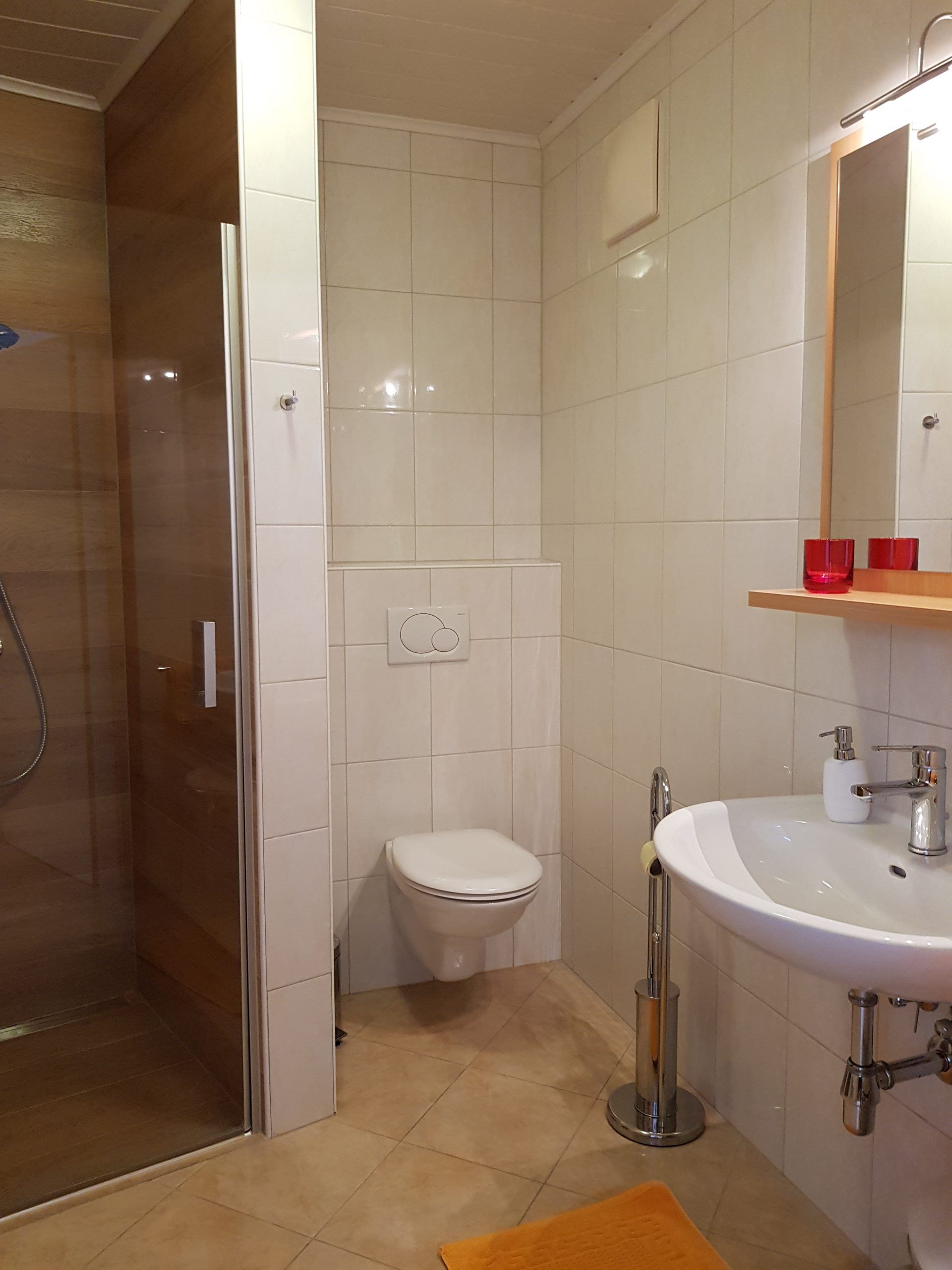 Moderní koupelna se sprchovým koutem, toaletou a umyvadlem.