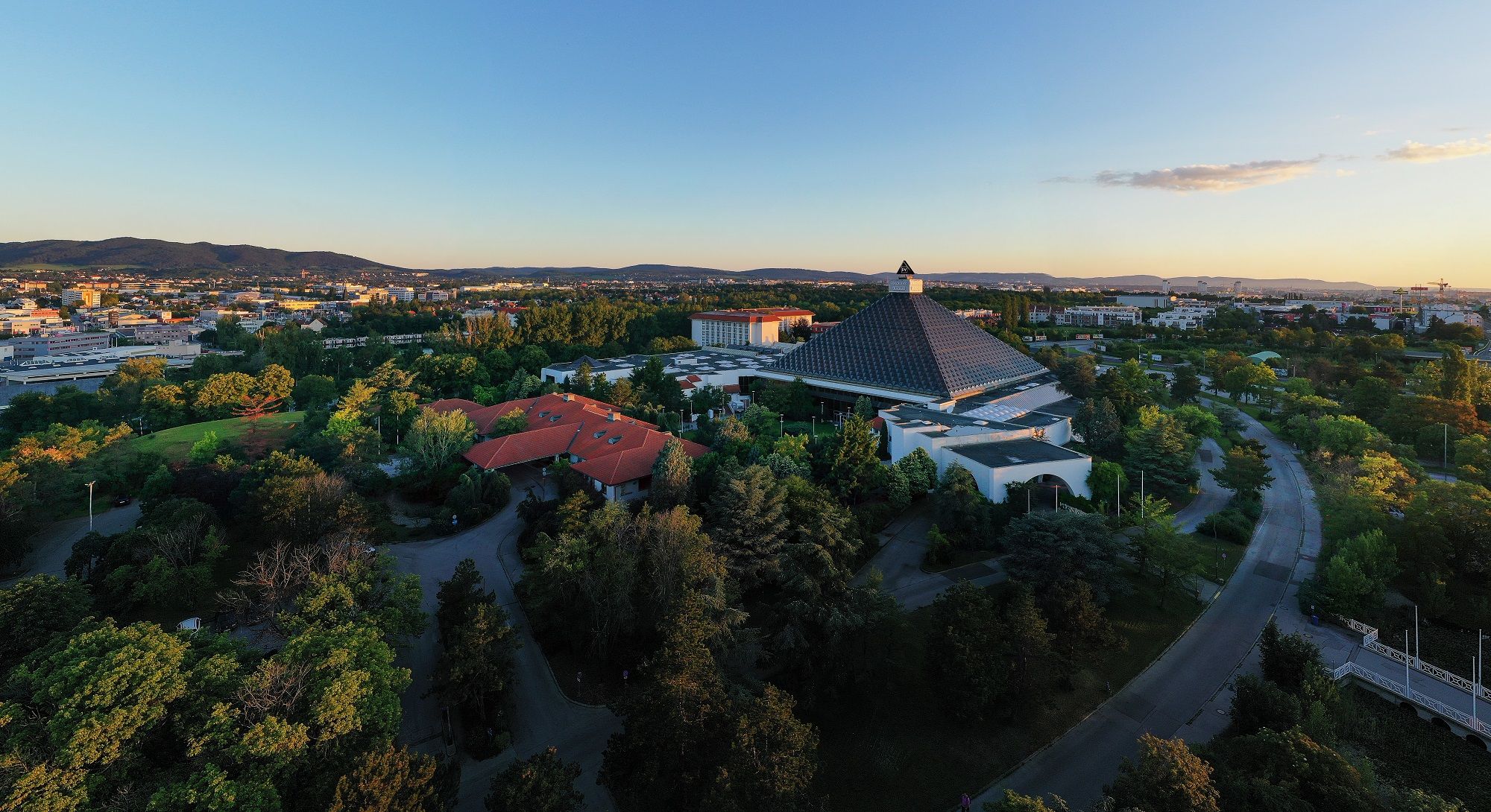 Letecký pohled na Eventhotel Pyramide s okolní krajinou při západu slunce.